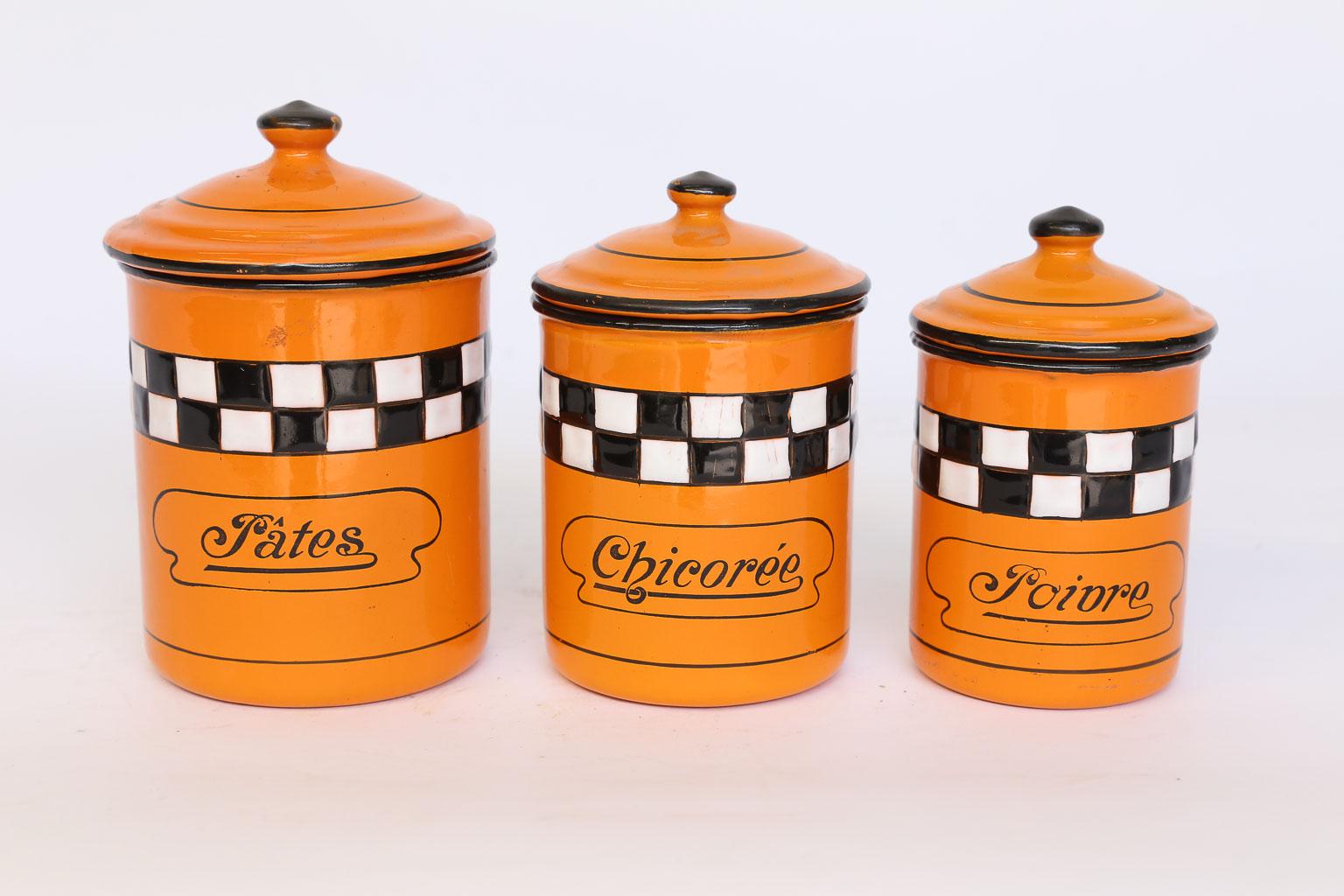 This French enamel canister set consists of three, graduated, lidded canisters. The canisters are enamel, orange with a black and white checkerboard and black lettering. Pates - Pasta, 6