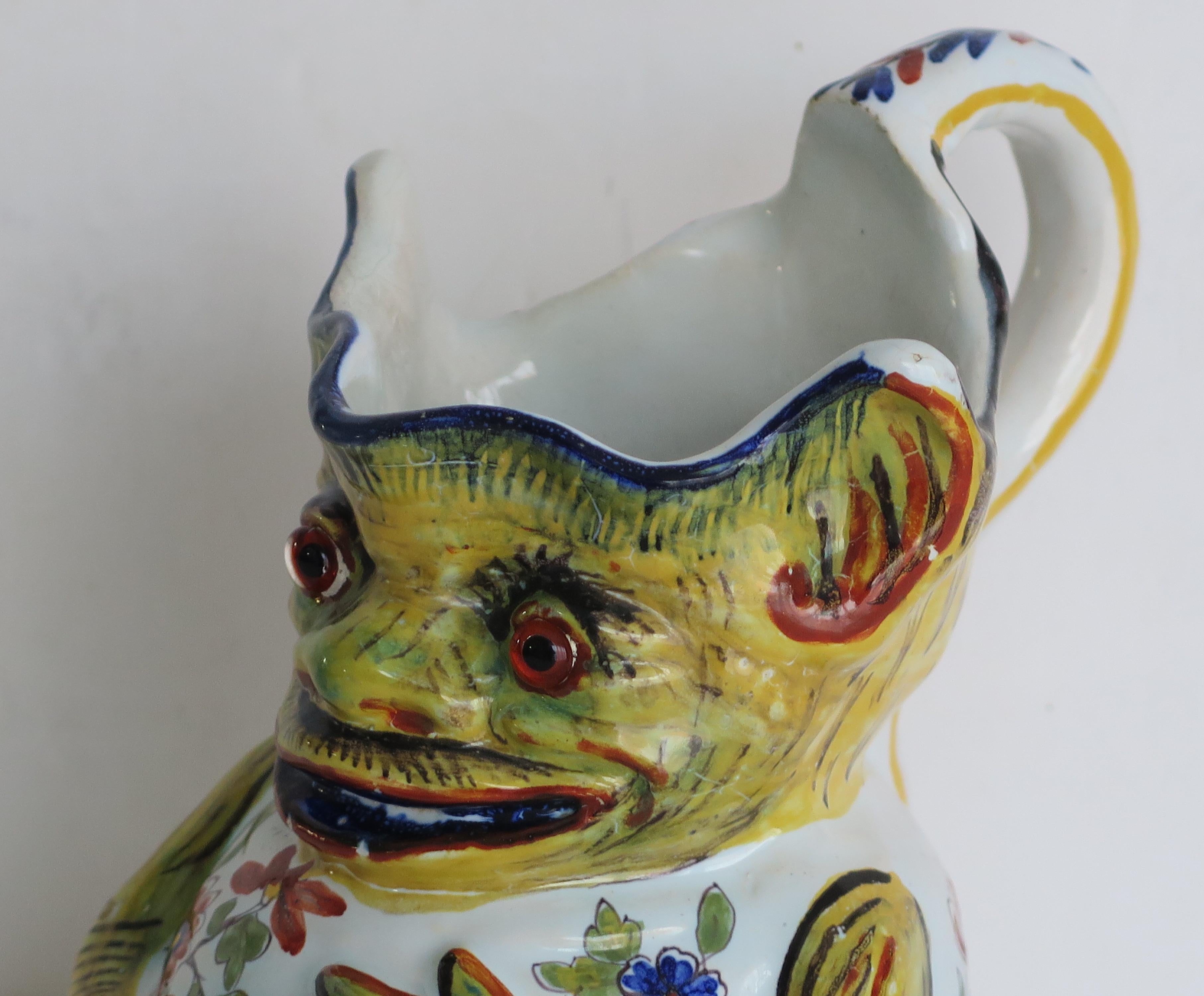 This is a very interesting Faience Jug, which we attribute to being made in France during the middle of the 19th century.

The jug is well potted in the shape of a grotesque Imp with a loop handle.

lt is all hand painted with bold coloured
