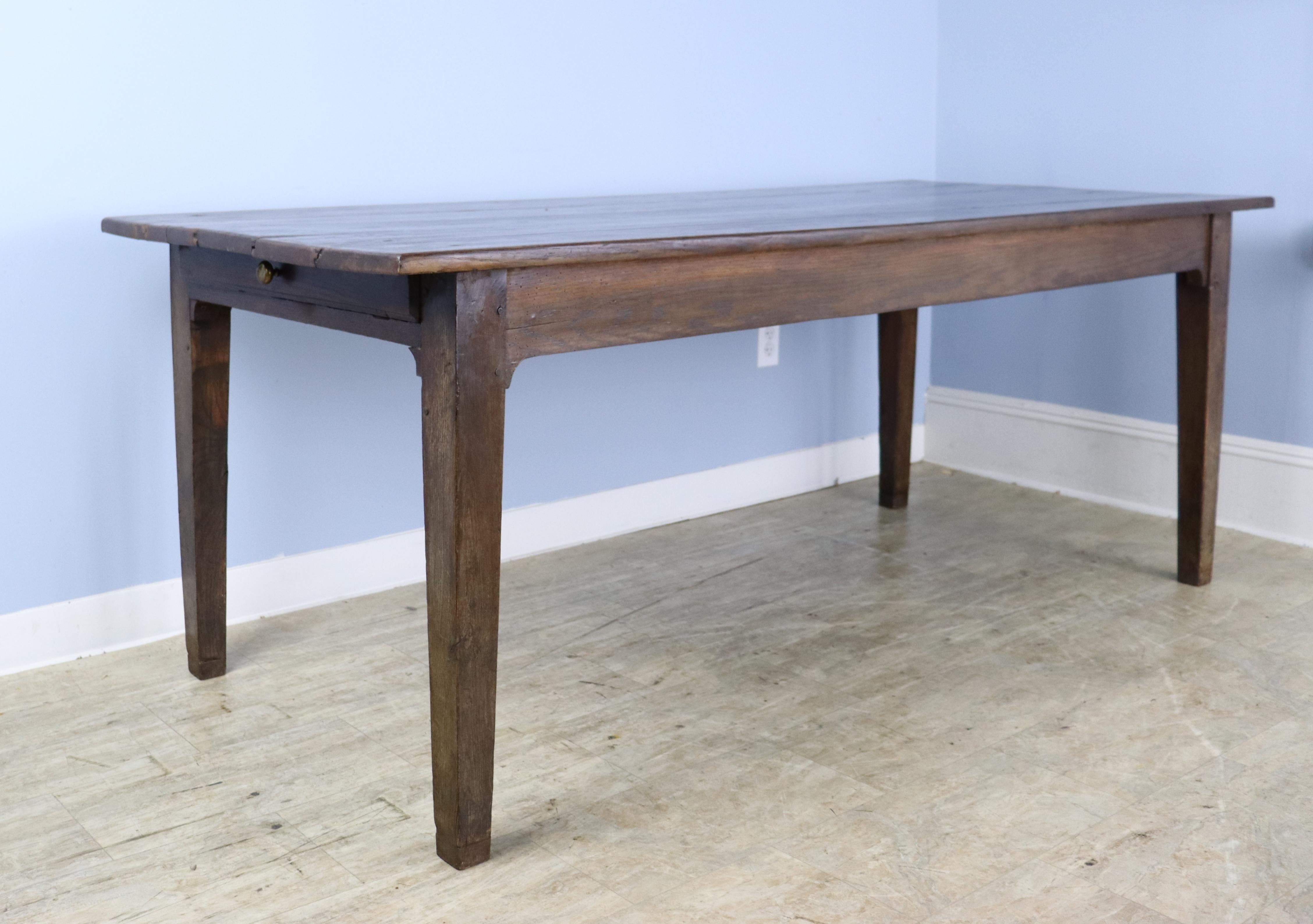 A handsome French chestnut dining or farm table with rich color and nice patina. This table has a single roomy drawer with divided space. Apron height of 24.5 inches is very good for knees and there are 66.5 inches between the legs on the long side.