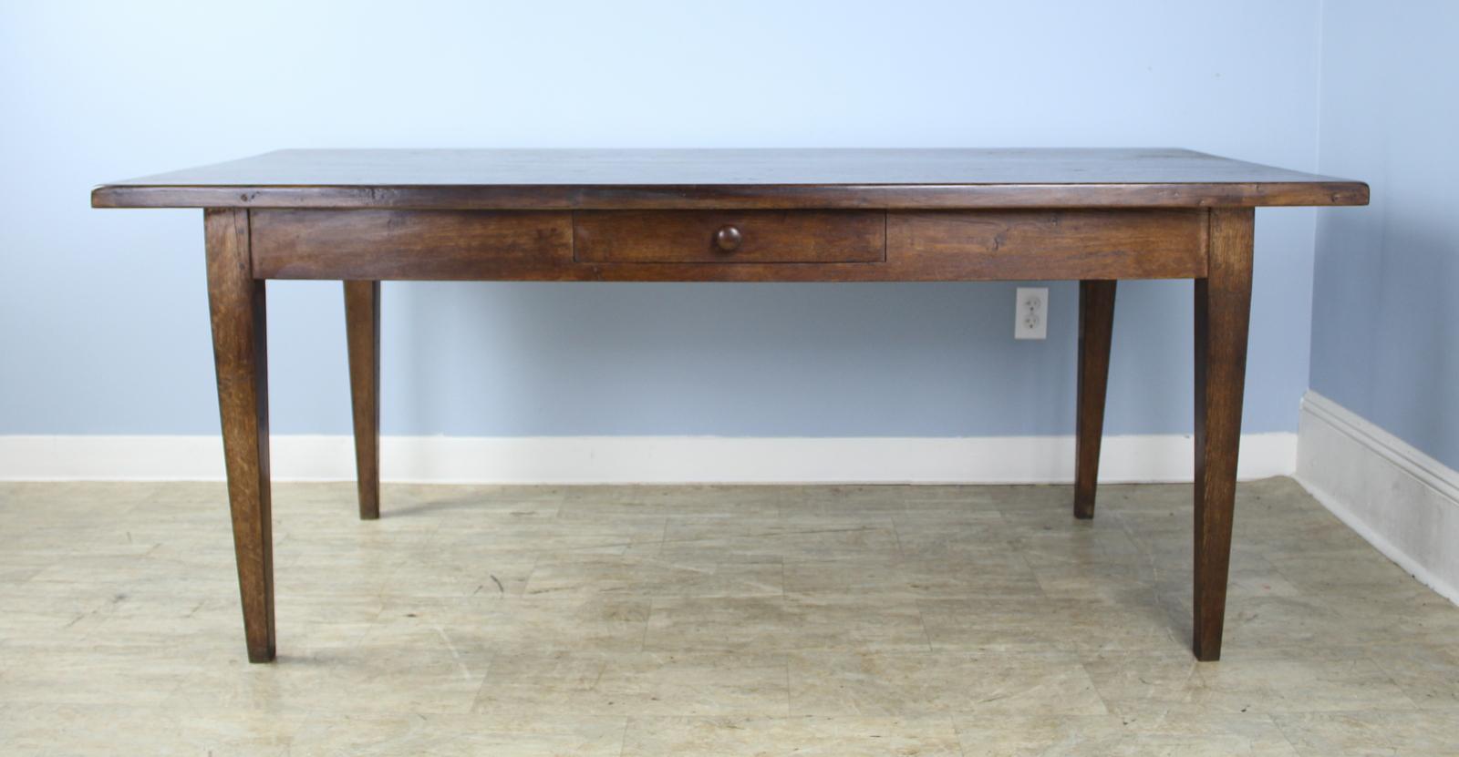A handsome French dining or farm table with rich color and nice patina. This table has a charming single drawer. Apron height of 24 inches is very good for knees and there are 56.5 inches between the legs on the long side.