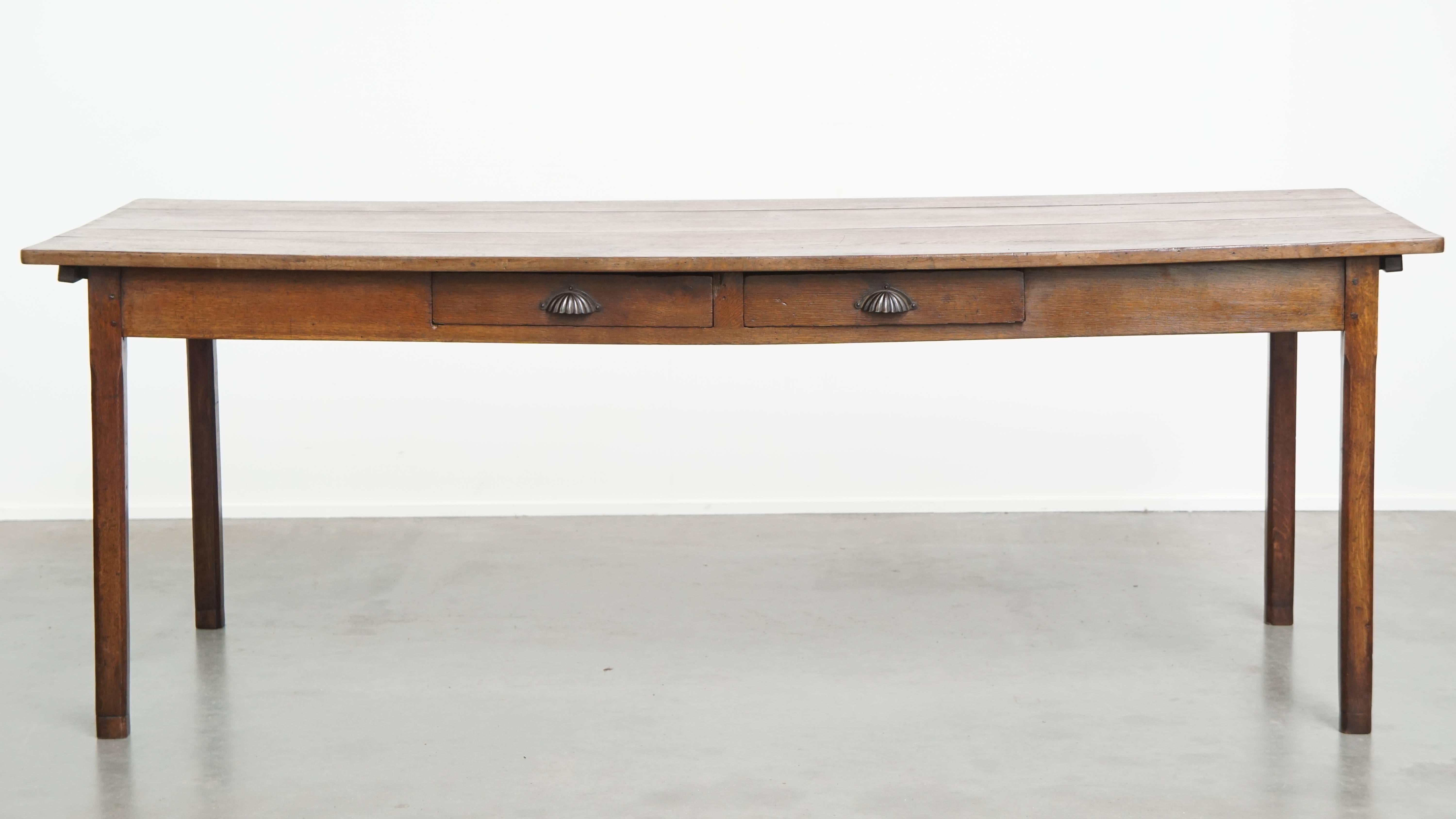 Offered here this beautiful large antique French farmhouse dining table from 1800, made of oak with 2 drawers and original details.
This spacious and characterful antique French farmhouse dining table, dating back to 1800, fits into almost any