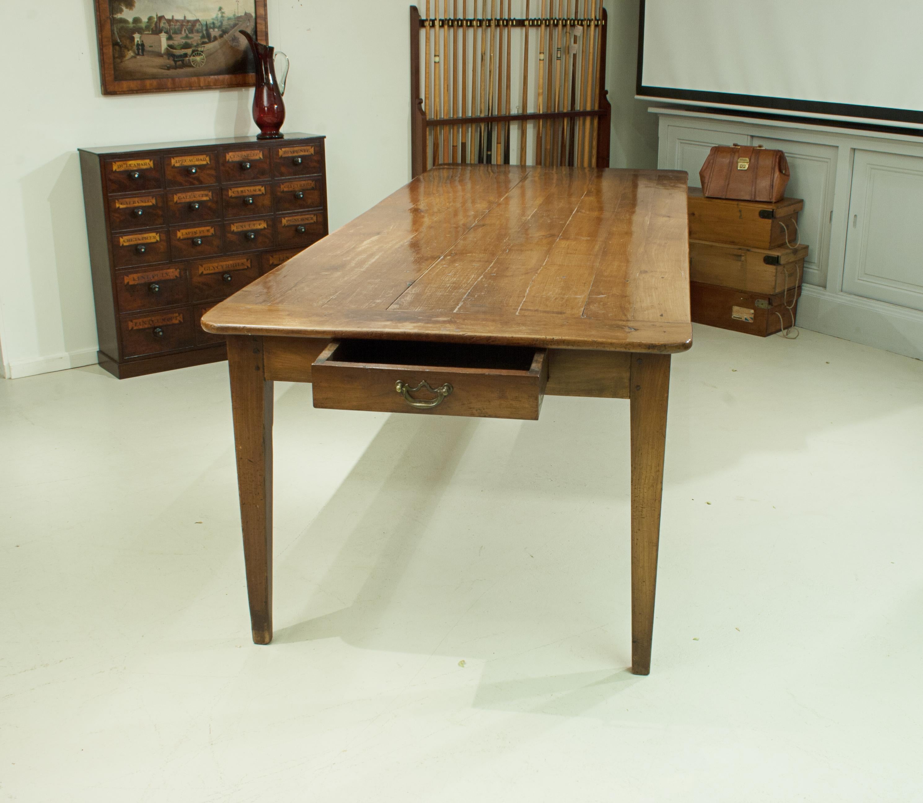 Large French fruit wood farm house table.
19th century country French farm house table assembled in the traditional method of pegged mortise and tenon joints. A drawer is at one end, the other has a bread slide. The top is of an eight plank