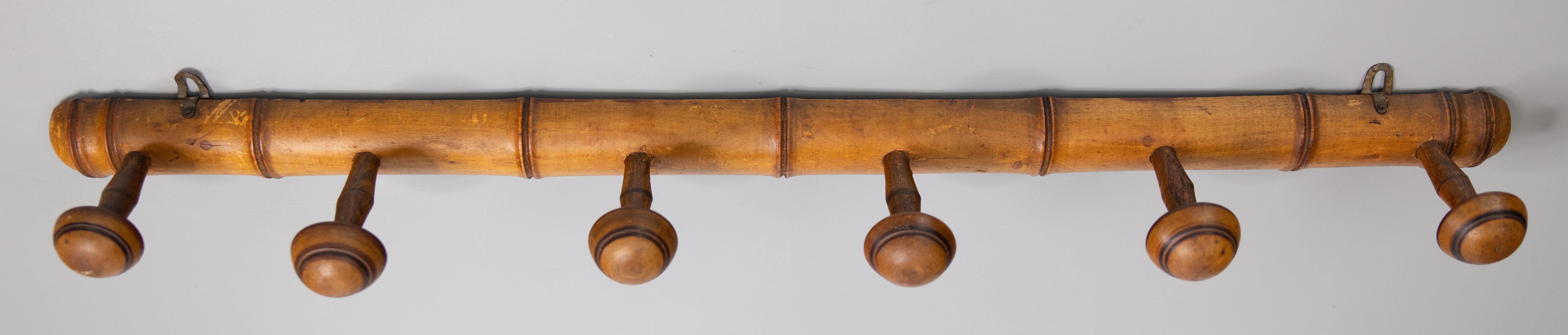 A superb antique French faux bamboo carved wood coat rack, circa 1920. This fine rack is a nice large size and retains the lovely original surface and patina with six hand turned pegs, perfect for hanging jackets and hats in an entryway or
