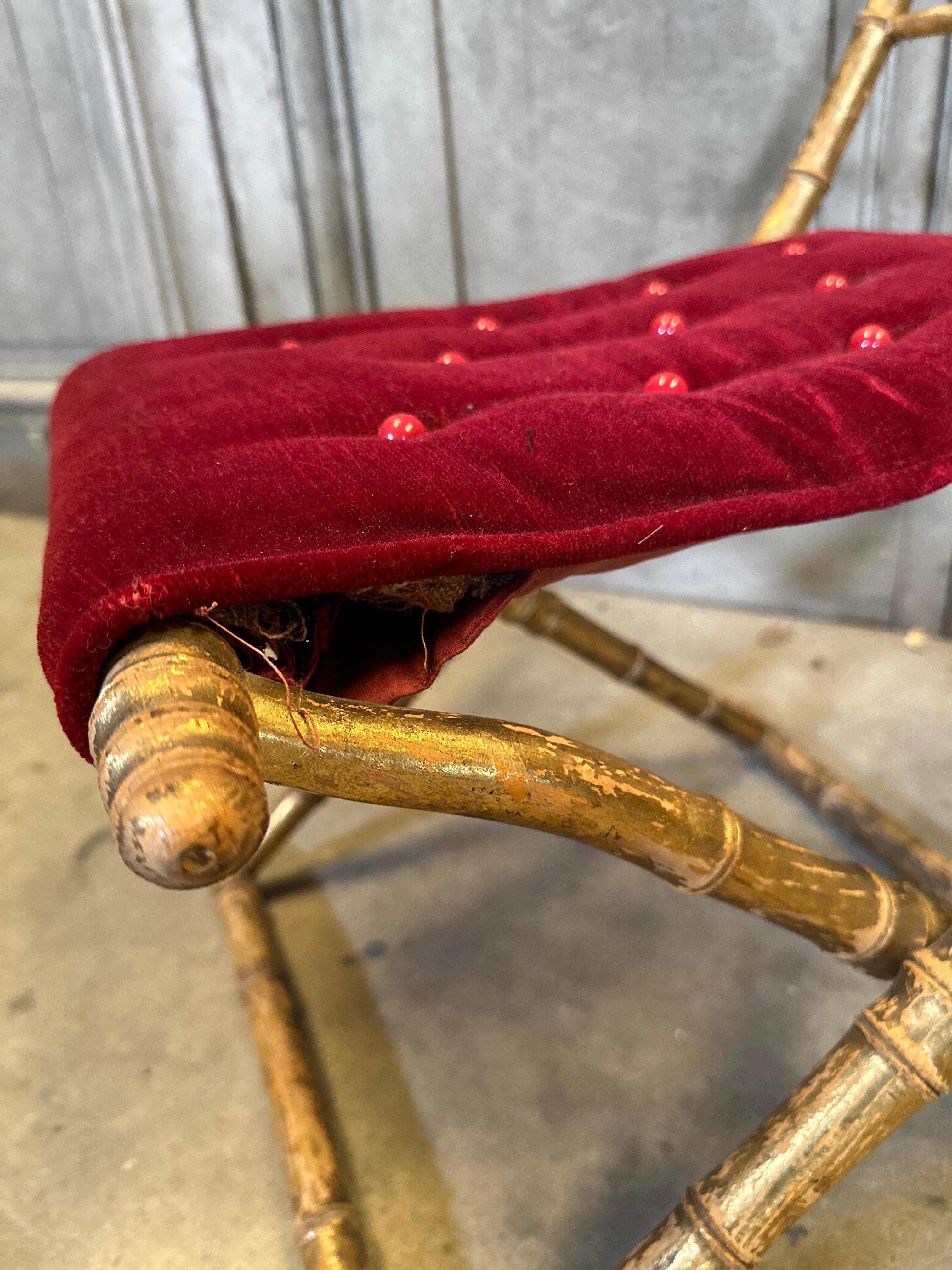 Lovely and unique, this French folding stool has carved and gilt faux bamboo legs and includes a richly upholstered top in a royal red velvet. Can be used as a footstool but also would be a lovely addition to a guest suite to hold luggage or could