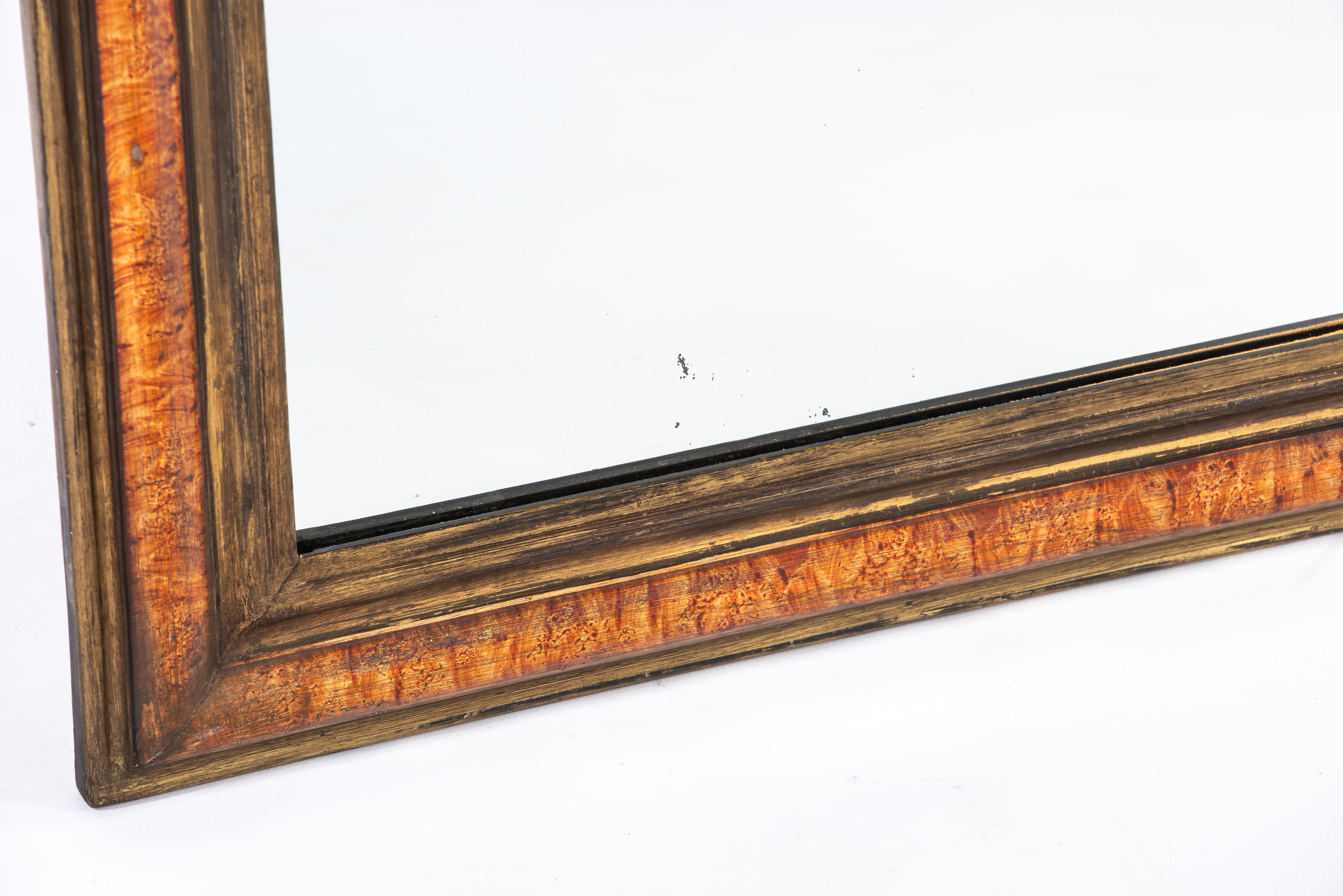 On offer here is a beautiful Louis Philippe mirror that was made in Northern France in the late 1800s. The mirror has a solid pine frame that was smoothened with gesso. The mirror frame is painted to resemble the exquisite wood species that is burl