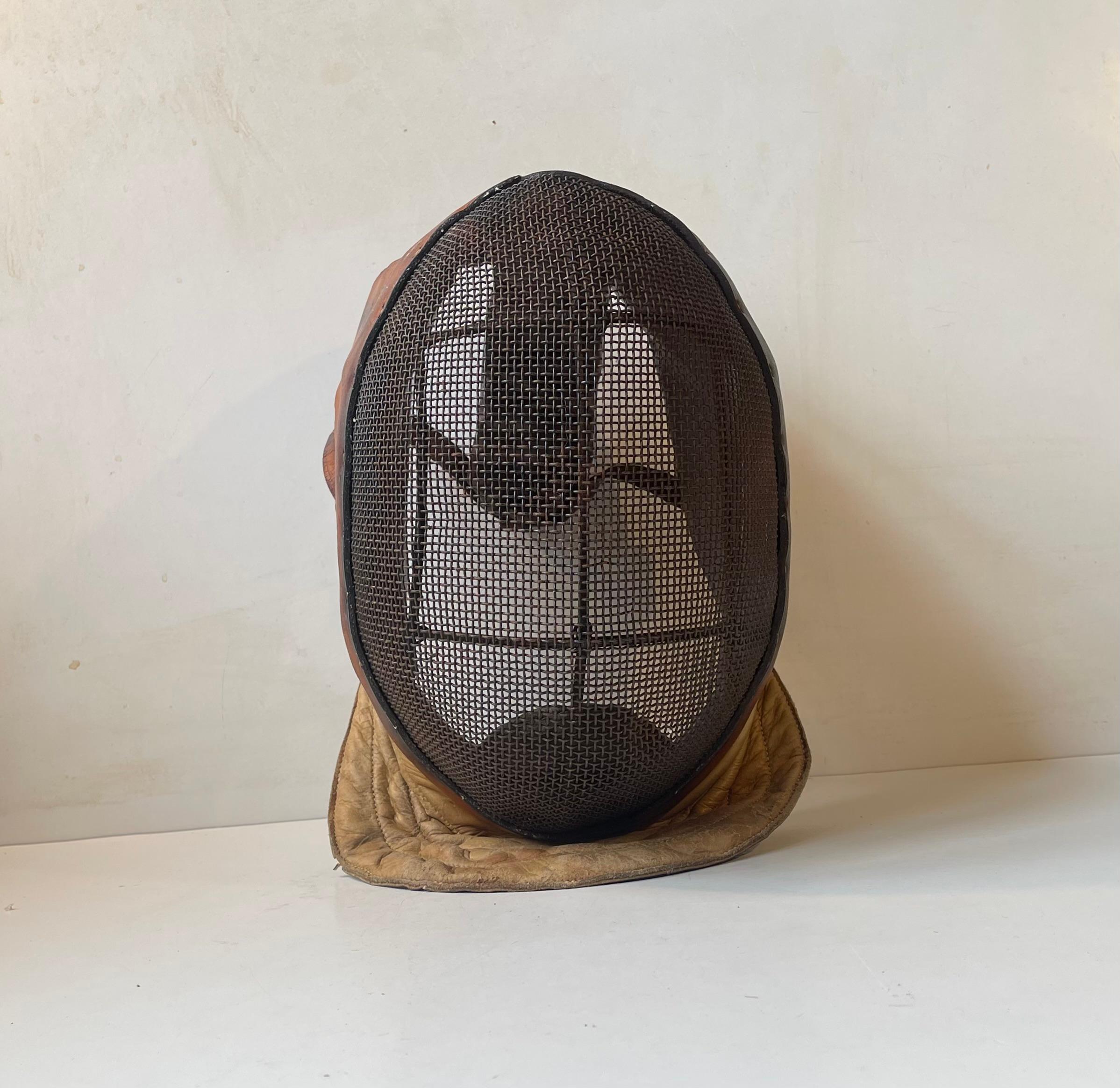 Raw authentic fencing mask that tics all the right boxes. It has such a masculine and brutal appearance. Thick patinated leather and dark metal face-cover sets the tone for this highly decorative piece. It was made in France during the 1920s or 30s