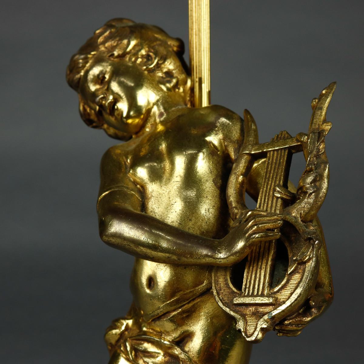 An antique French figural table lamp offers cast and gilt metal base with classical cherub and lyre sculpture, seated on pierced foliate base, circa 1900

***DELIVERY NOTICE – Due to COVID-19 we have employed LIMITED-TO-NO-CONTACT PRACTICES in the