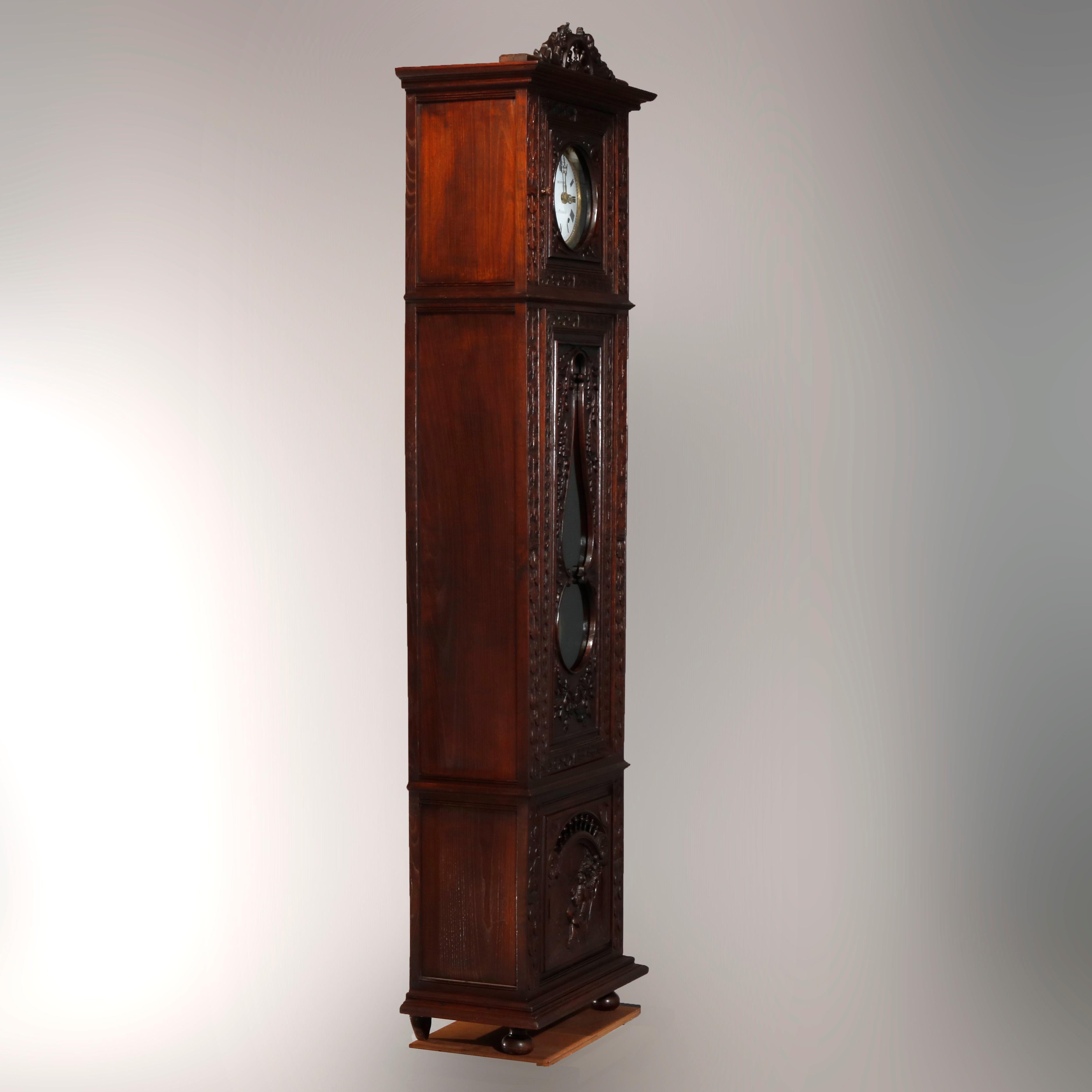 An antique Continental French figural longcase clock by Besnard a Chateauin offers deeply carved oak case with crest having central wheel and flanking music men surmounting case with high relief carving throughout and terminating in base with scene