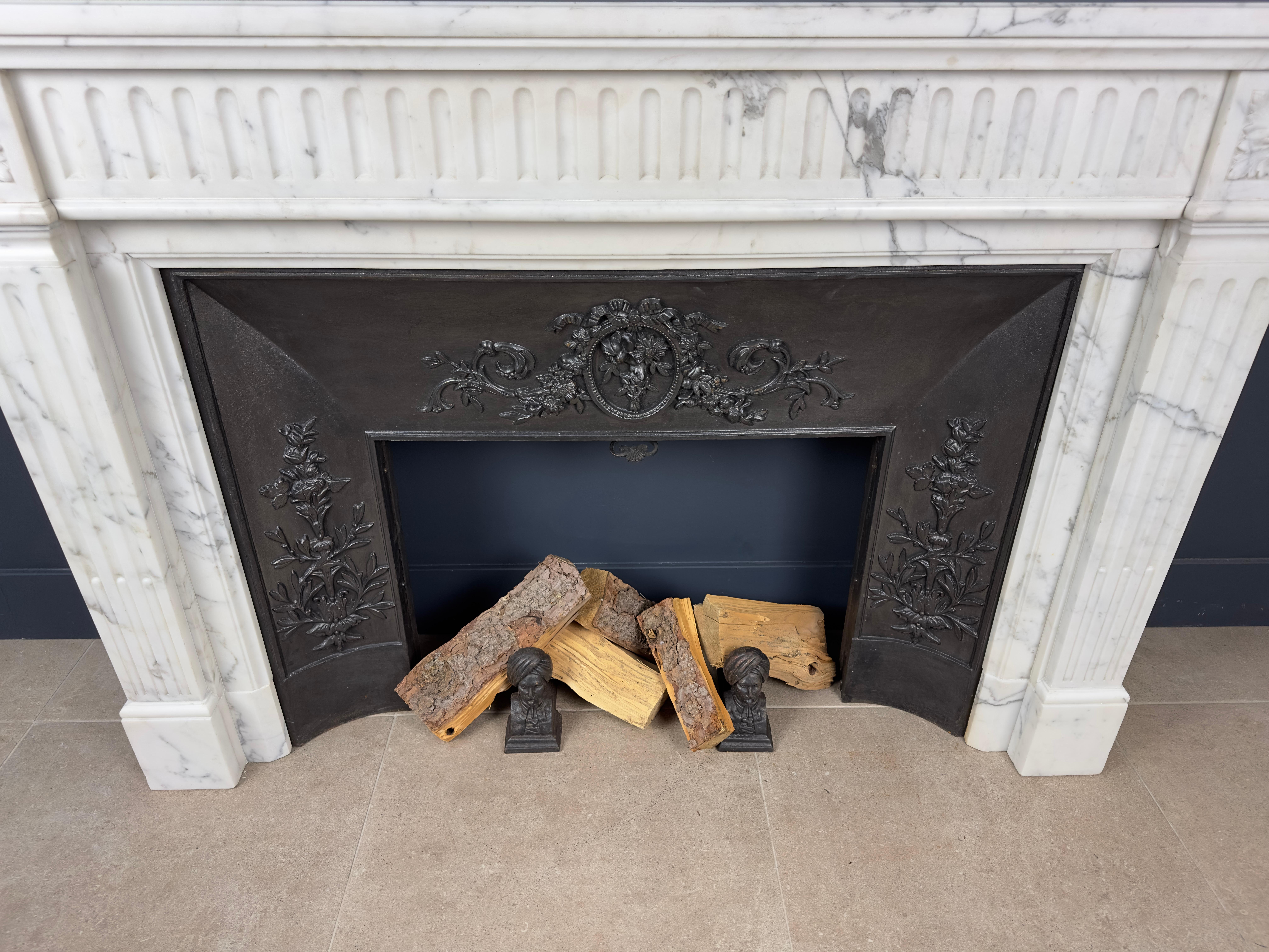 

Step back in time with our Antique French Carrara Marble Fireplace, a true gem that reflects the elegance of days gone by. The Carrara marble gives this fireplace a timeless splendor, and the beautiful cast iron insert adds a chic detail that