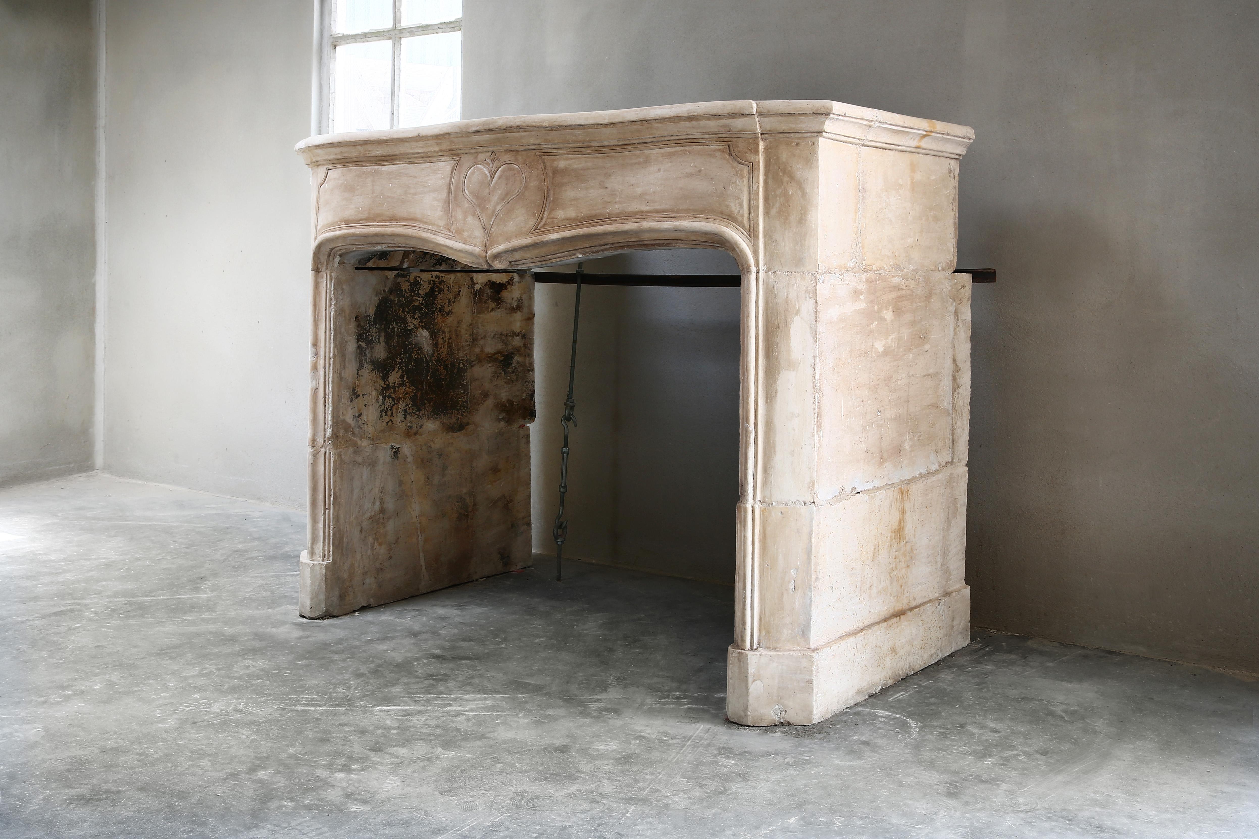 Antique French fireplace of limestone from the 19th century! The front part has an ornament in the shape of a heart that we do not often encounter with antique fireplaces. The antique fireplace has a beautiful neutral color that is well applicable
