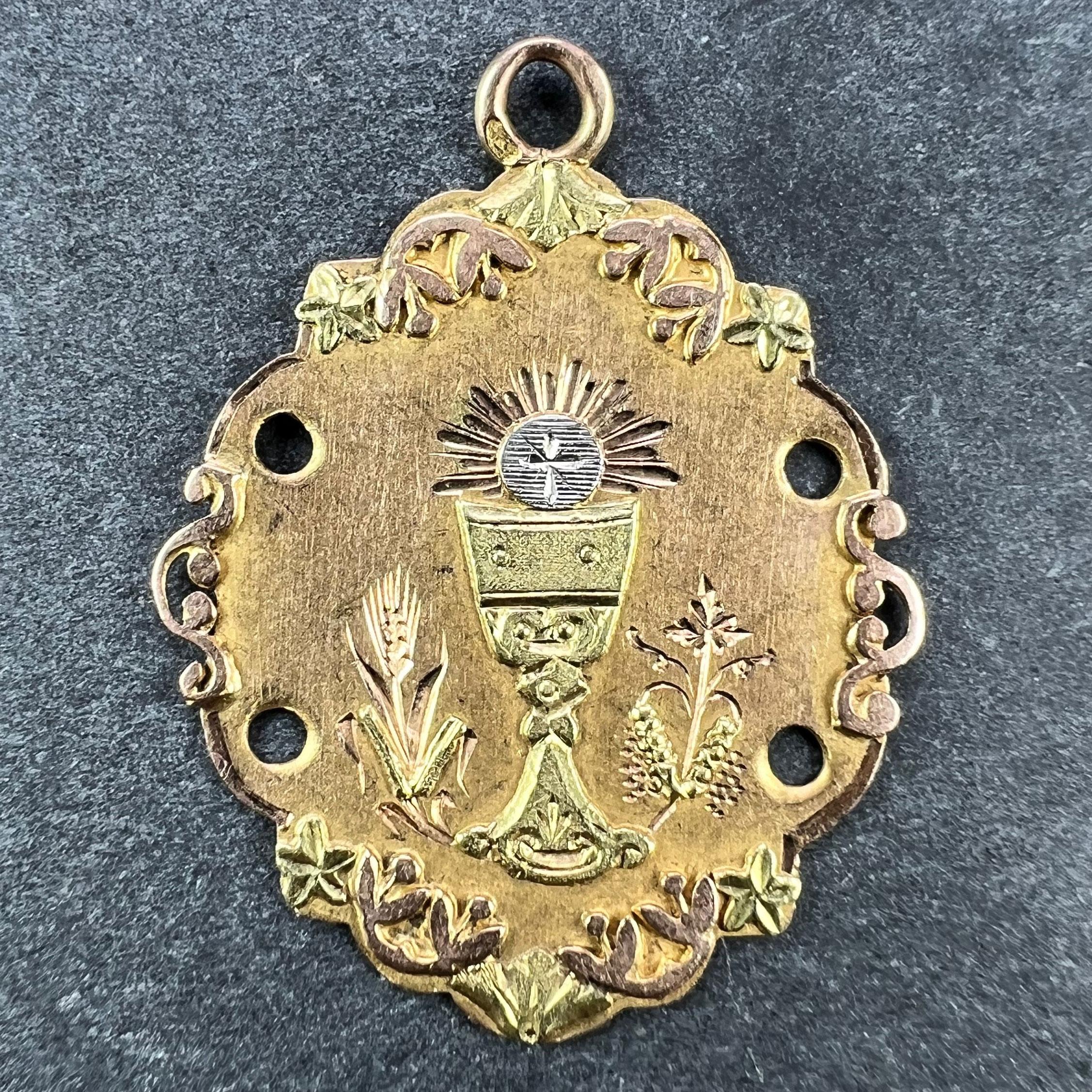 Pendentif à breloque français en or 18 carats (18K) conçu comme une médaille en or rose représentant un calice ou une coupe sainte en or jaune avec une hostie en or blanc au-dessus, rayonnant de lumière pour célébrer une première communion. Le
