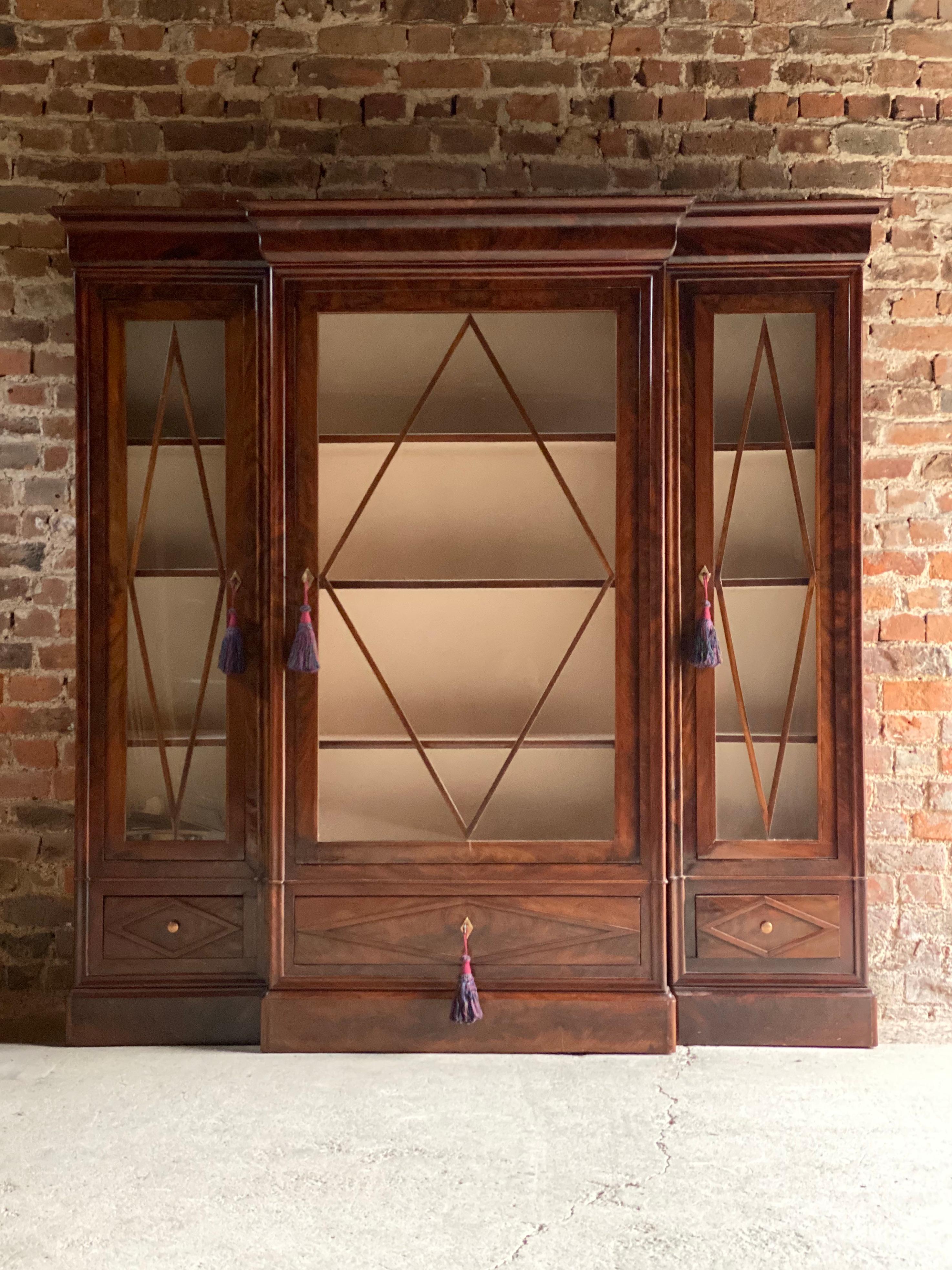 A magnificent late 19th century French flamed mahogany three-door glazed breakfront display cabinet bibliotheque circa 1890, the overhanging cornice above three glazed doors with lozenge shaped deign panels, cream lined interior with adjustable