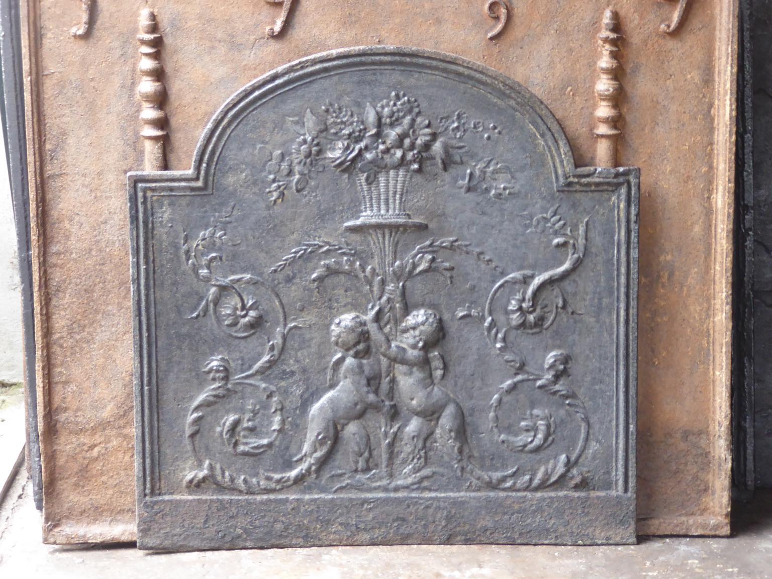 18th-19th century French neoclassical fireback with two cupids holding a flower basket.

The fireback is made of cast iron and has a black patina. The fireback is in a good condition. It does not have cracks.







 