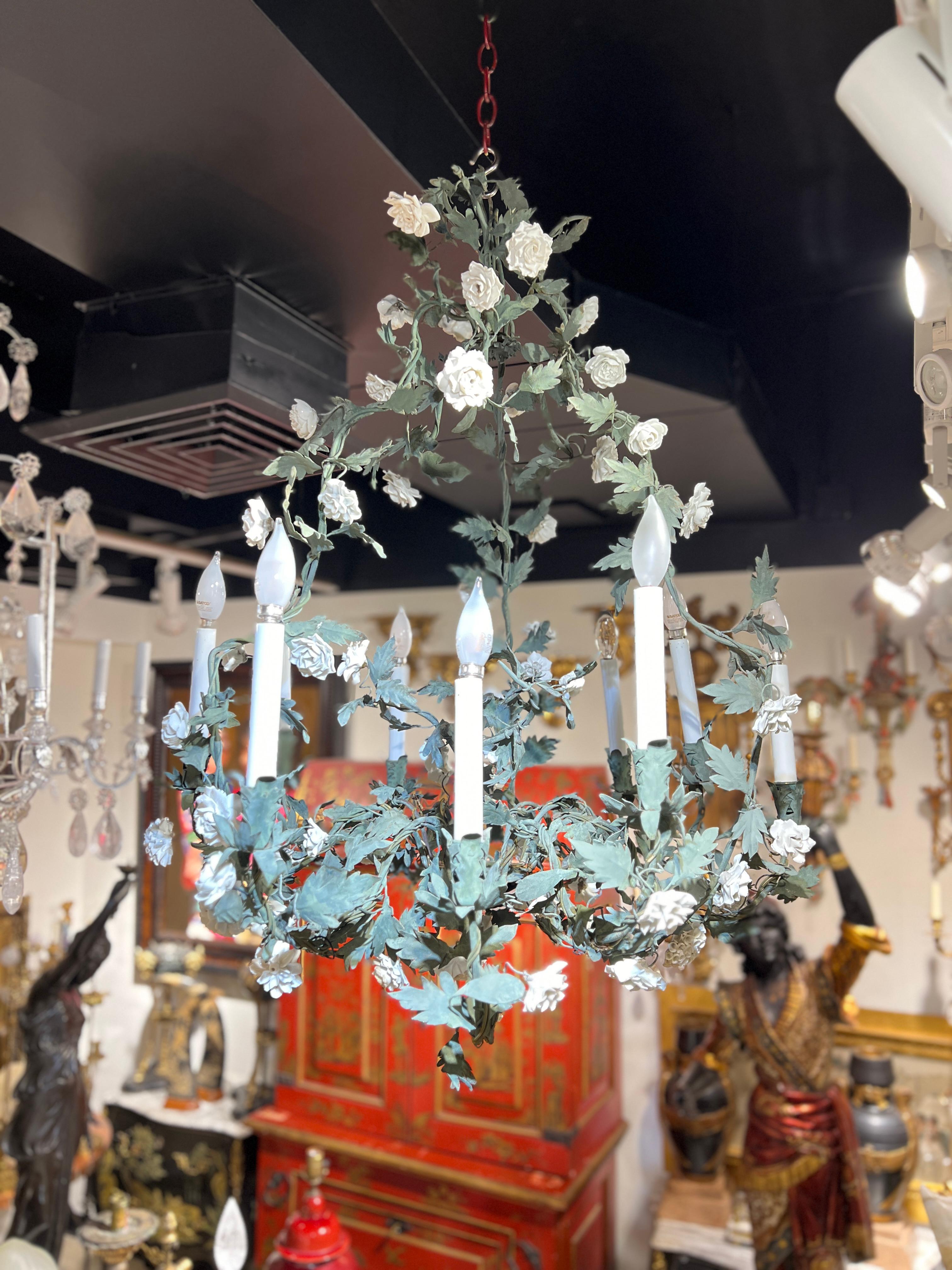 Lovely antique (early 20th century) chandelier in the French Louis XV style,  crafted from metal with forest green patina, featuring white flower heads and nine candle arms with candelabra size sockets, clean white plastic candle covers and bulbs. 