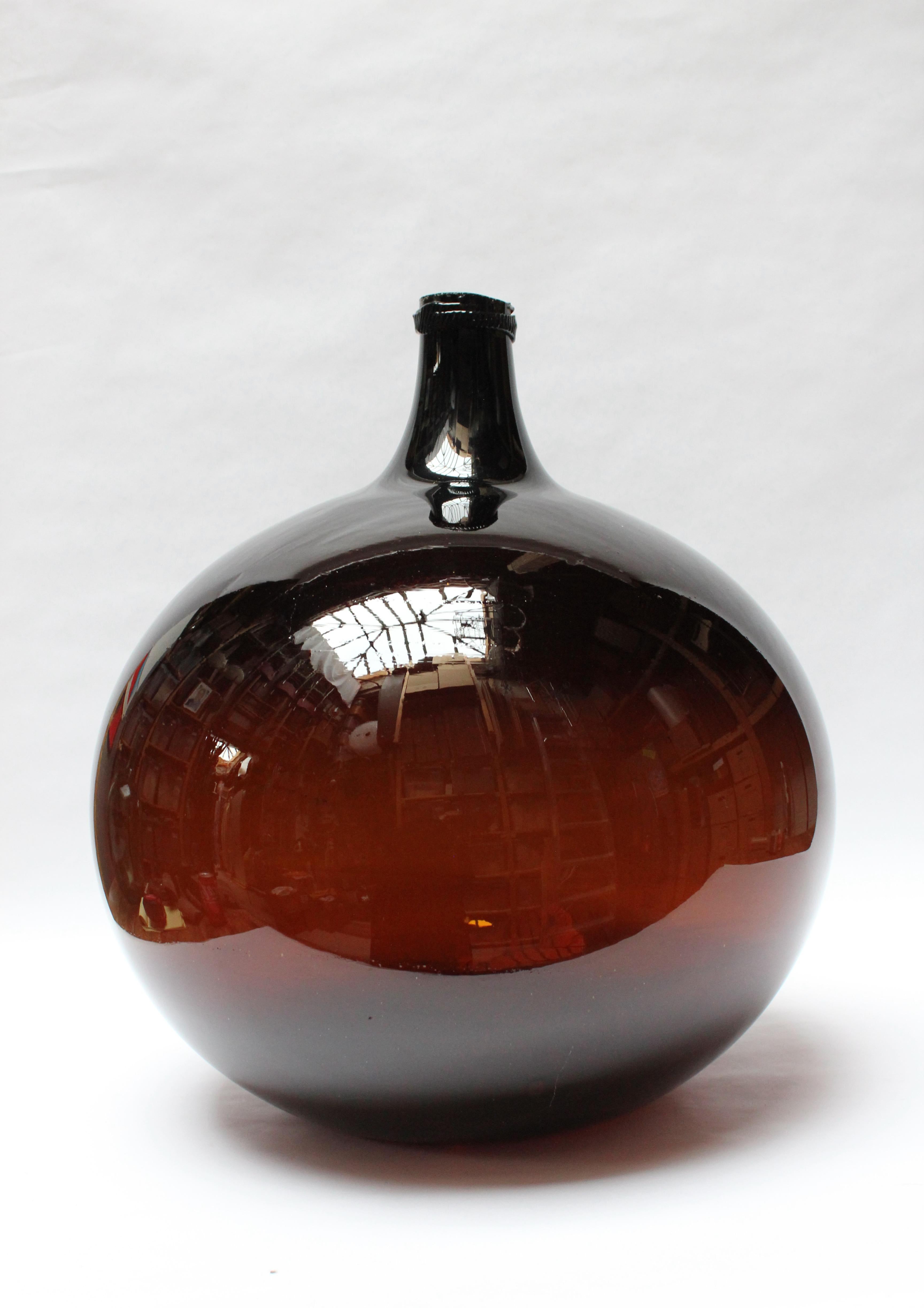 Impressive French Demijohn / Bonbonne Ambrée Brune originally used for transporting wine (ca. early 19th Century, France). Composed of free-blown amber glass exhibiting large air bubbles within the glass itself with a sheared lip and applied glass