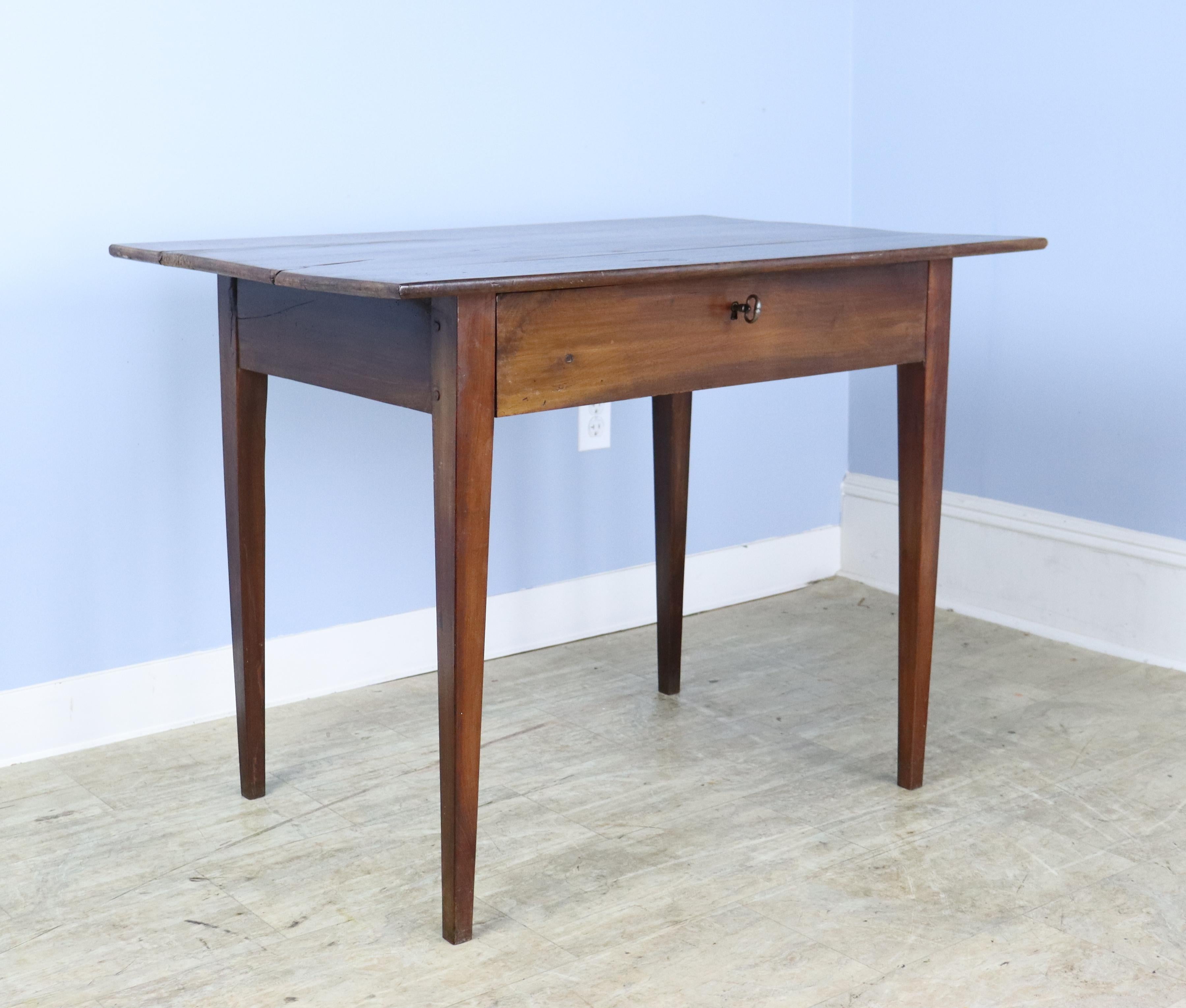 An elegant fruitwood side table with wonderful grain and color and a graceful thin top. Good tapered legs, pegged at the apron. The key does not turn in the lock but is attractive and useful as a drawer pull. Although this piece is generously