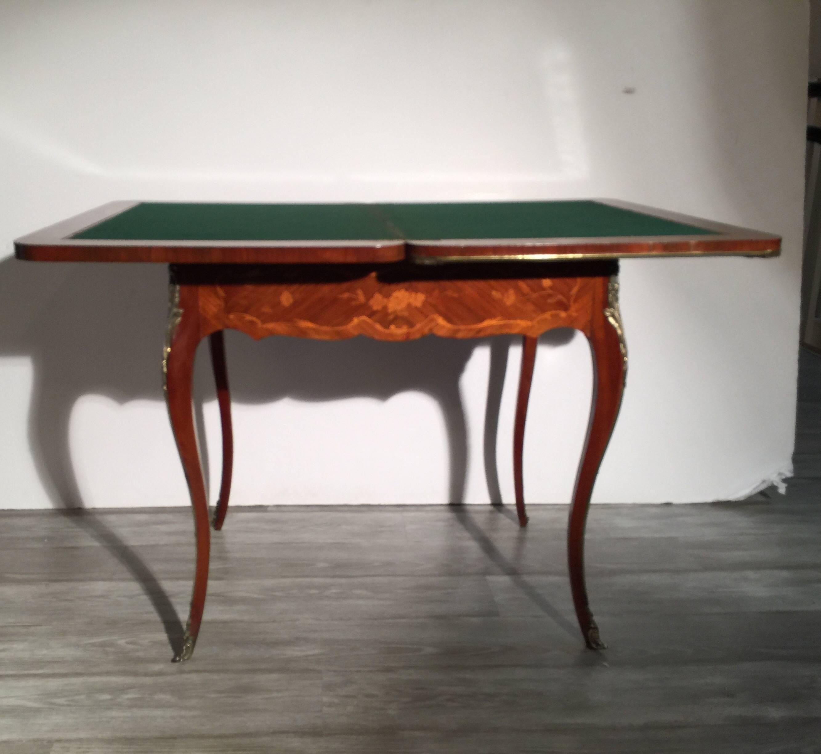 Intricately inlaid flip top game table in the Louis XV style. Kingwood, tulipwood and satinwood inlay with the edges in polished brass mounts. Recent French polish on the original finish. The top flips to double the size and is covered in green felt.