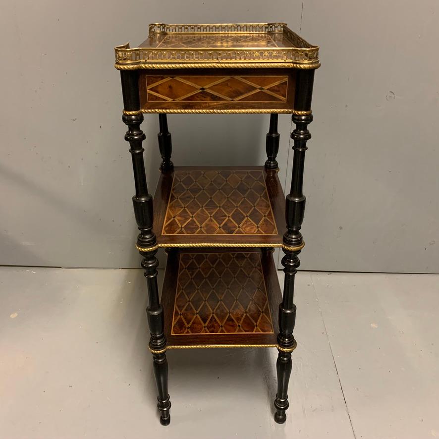 Beautifully made and very decorative French geometric amboyna and rosewood etagere side table with ebonized turned column supports and a 3/4 brass gallery top. Circa 1900 and in lovely original condition.
The table is made so it can free stand,