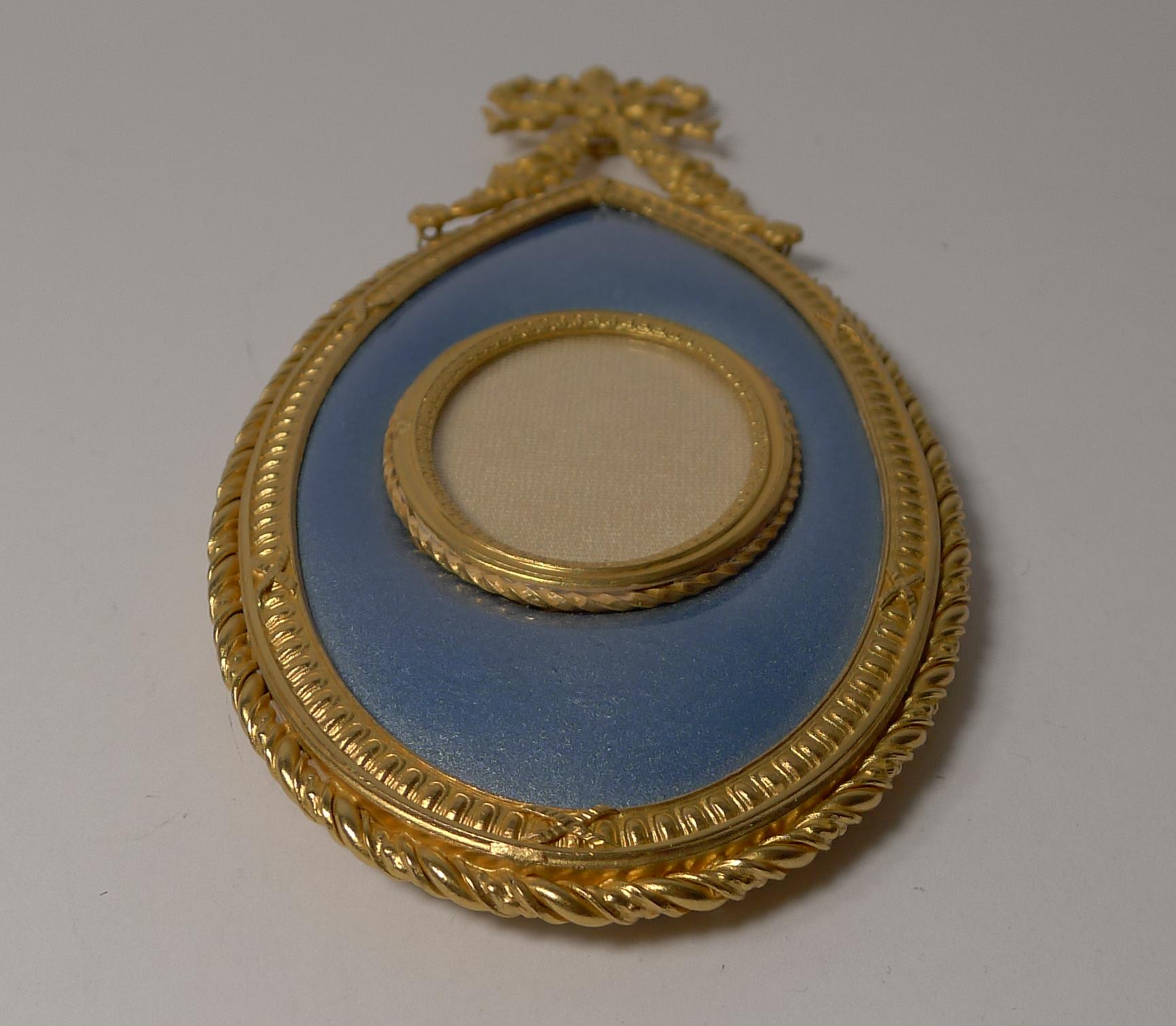 The front is inset with a fabulous blue enamel panel surrounding the central oval aperture. There is small ring to the back where the frame is hung on the wall.

Dating to circa 1900 it remains in superb condition having been fully restored to its