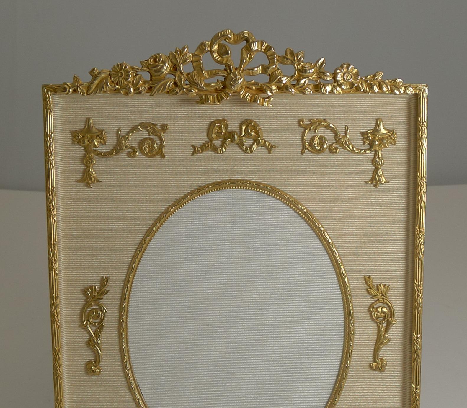 Pretty as a picture, this elegant French ormolu picture frame has been professionally restored to it's former glory, dating to circa 1900.

The top of the frame has a stunning gilded bronze ribbon and bow mount with exquisite mounts adorning the