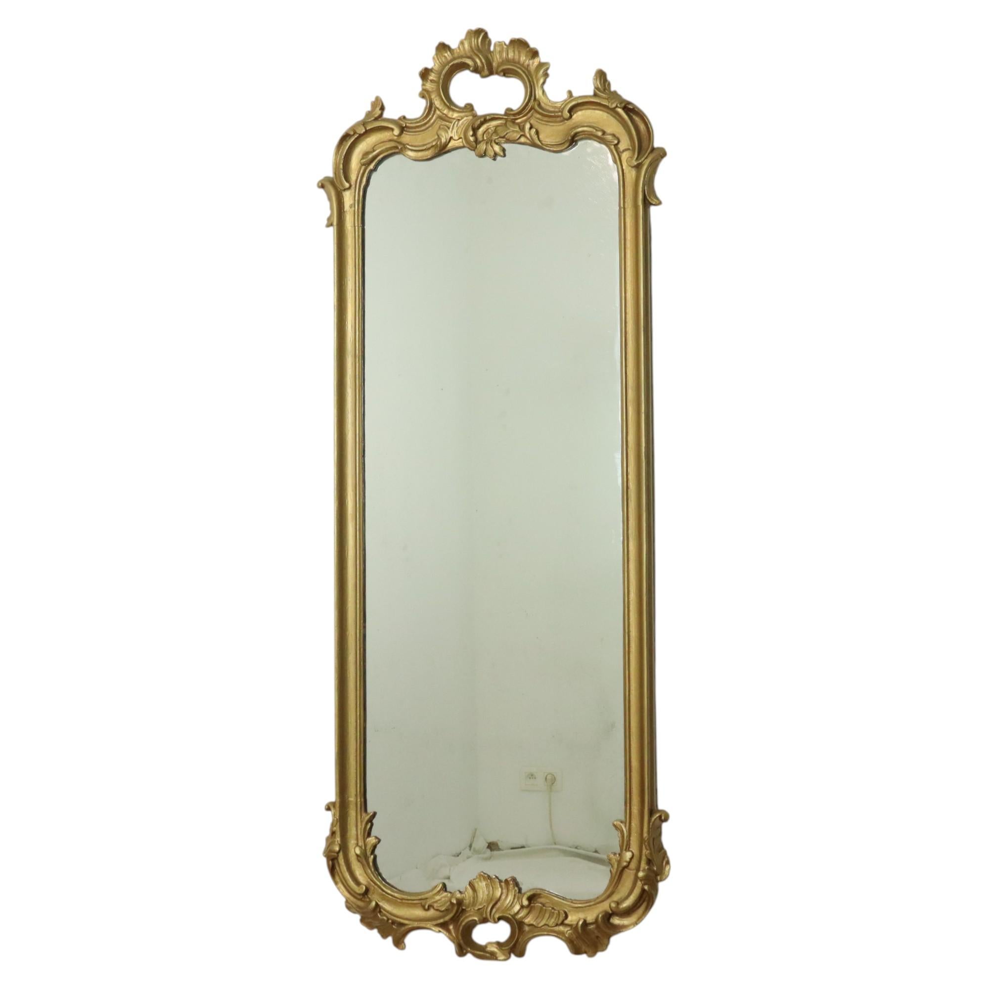 Grand miroir ancien étroit et doré du XIXe siècle, entièrement dans le style baroque classique, France vers 1870.

Le miroir possède encore sa plaque d'origine qui est décorativement altérée et simulée, ce qui est très souhaitable. Le cadre est