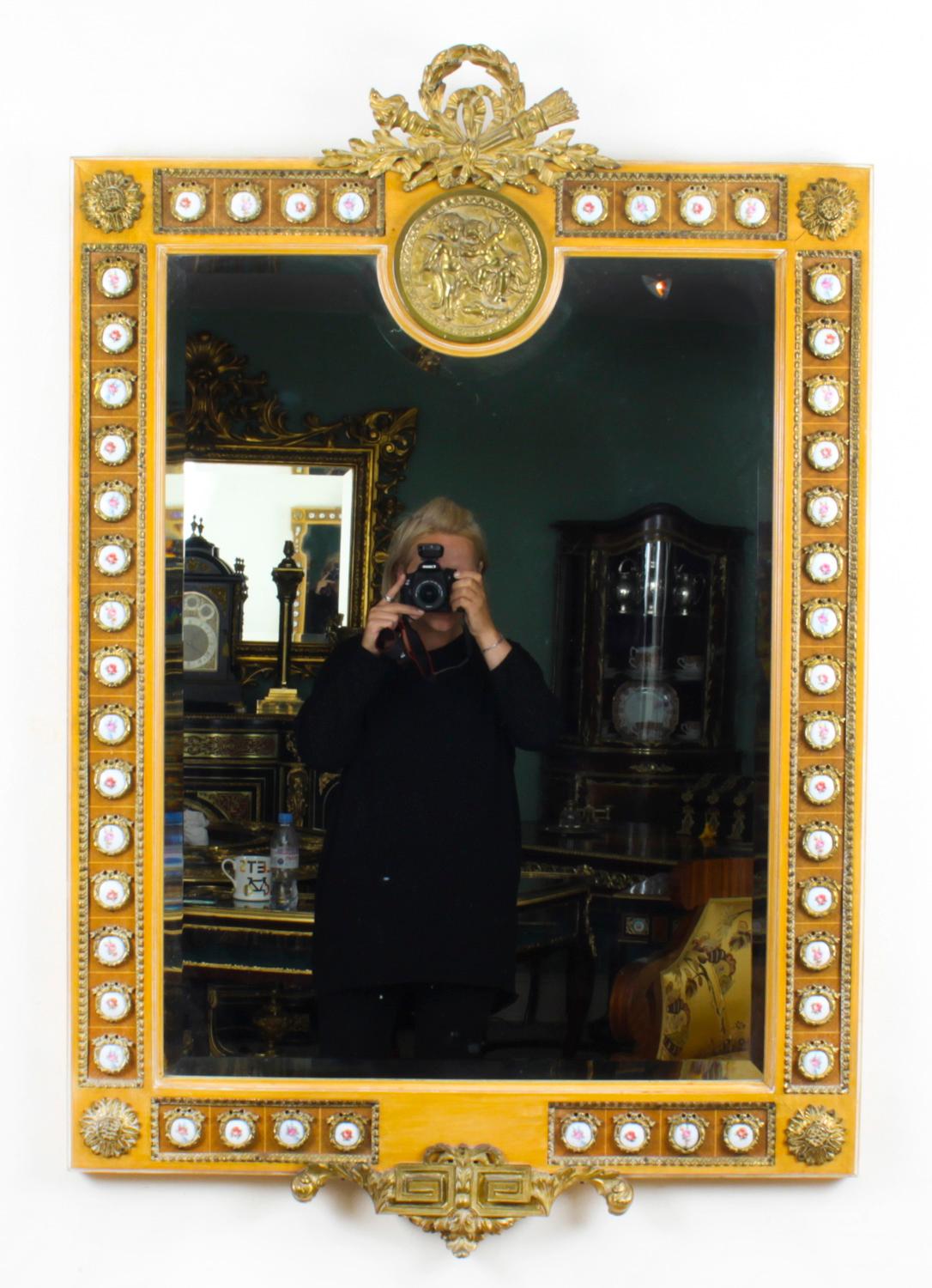 This is a fabulous French wall mirror style gilt and porcelain mounted, mid 20th century in date.

The beautifully carved rectangular mirror features a flaming torch and quiver surmount with Limoges style foliate painted cabochons surrounding the