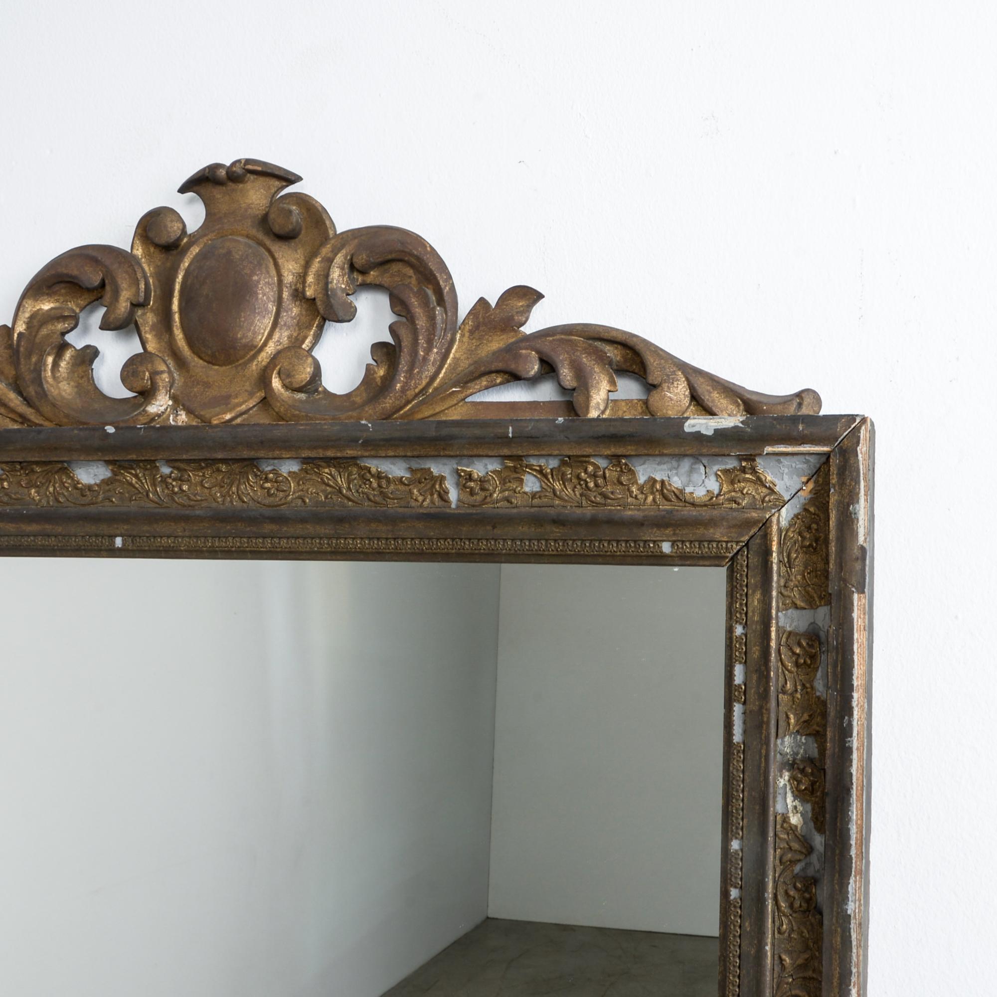 From France, circa 1900. Influenced by the era of French eclecticism, this mirror combines a floral crest motif with decorative plaster work; wrapped in gold leaf, seasoned by time.