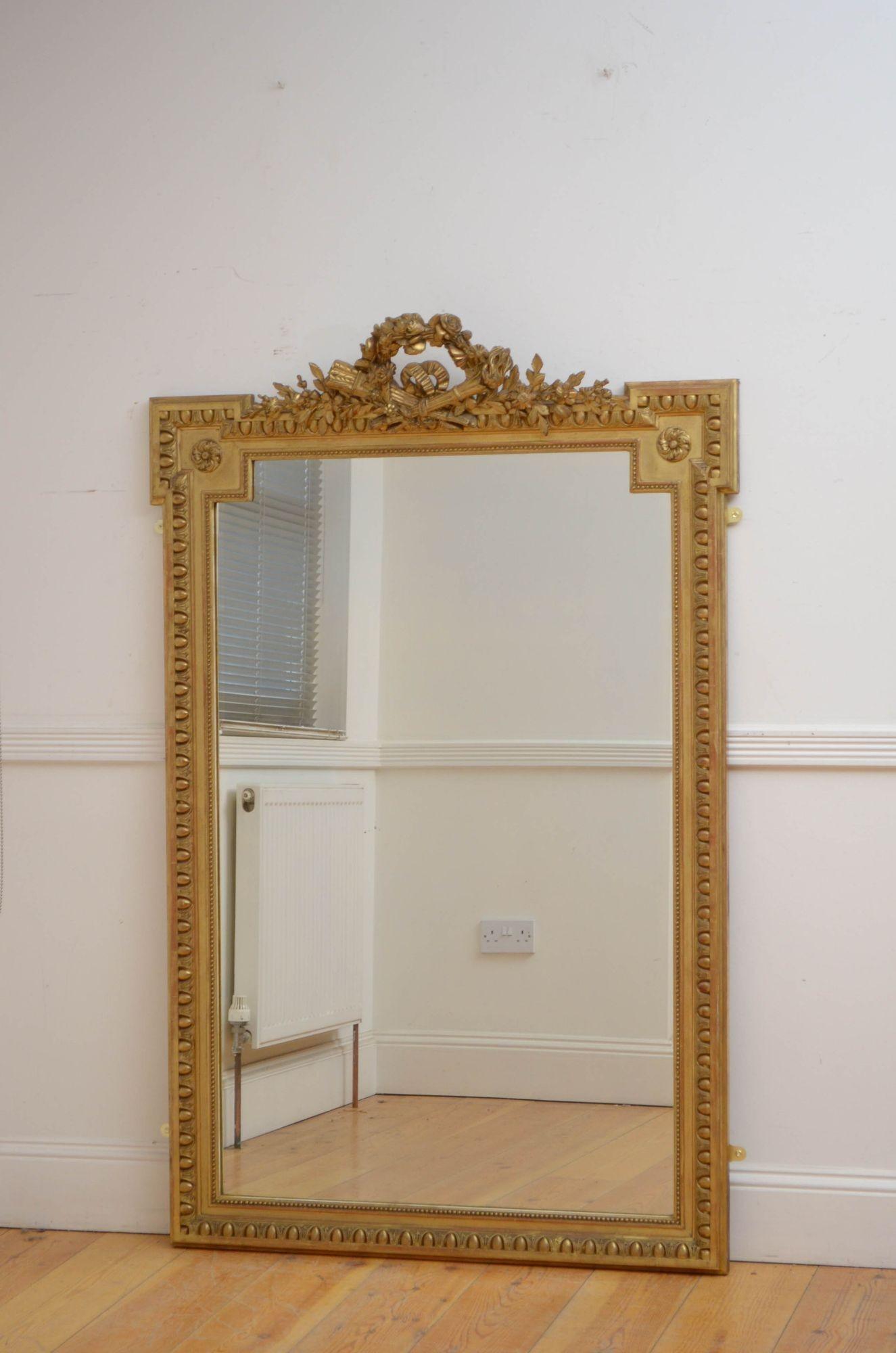 Sn5474 Fine 19th century French gilded wall mirror, having original glass with some imperfections in moulded, beaded and egg and dart carved giltwood frame with foliage centre crest decorated with a flowery bow. This antique mirror retains its