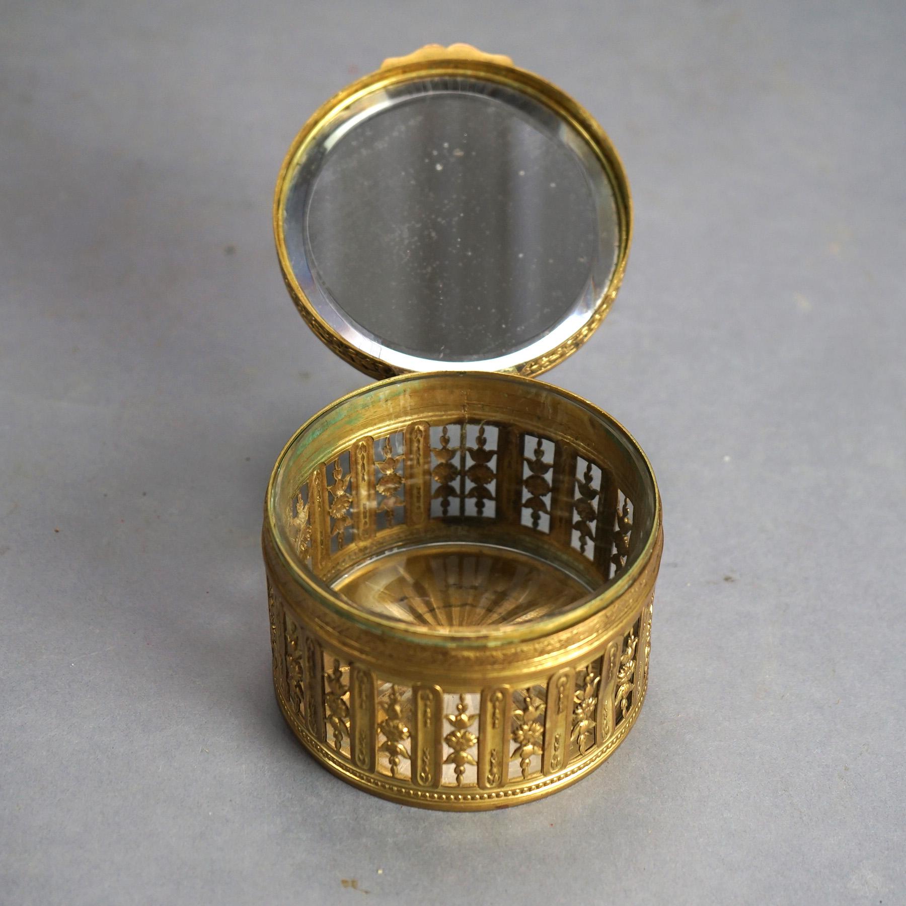 An antique powder box offers gilt brass construction with Guilloche enameled and hinged lid having central portrait and opening to mirrored interior over reticulated compartment with floral elements, en verso marked 