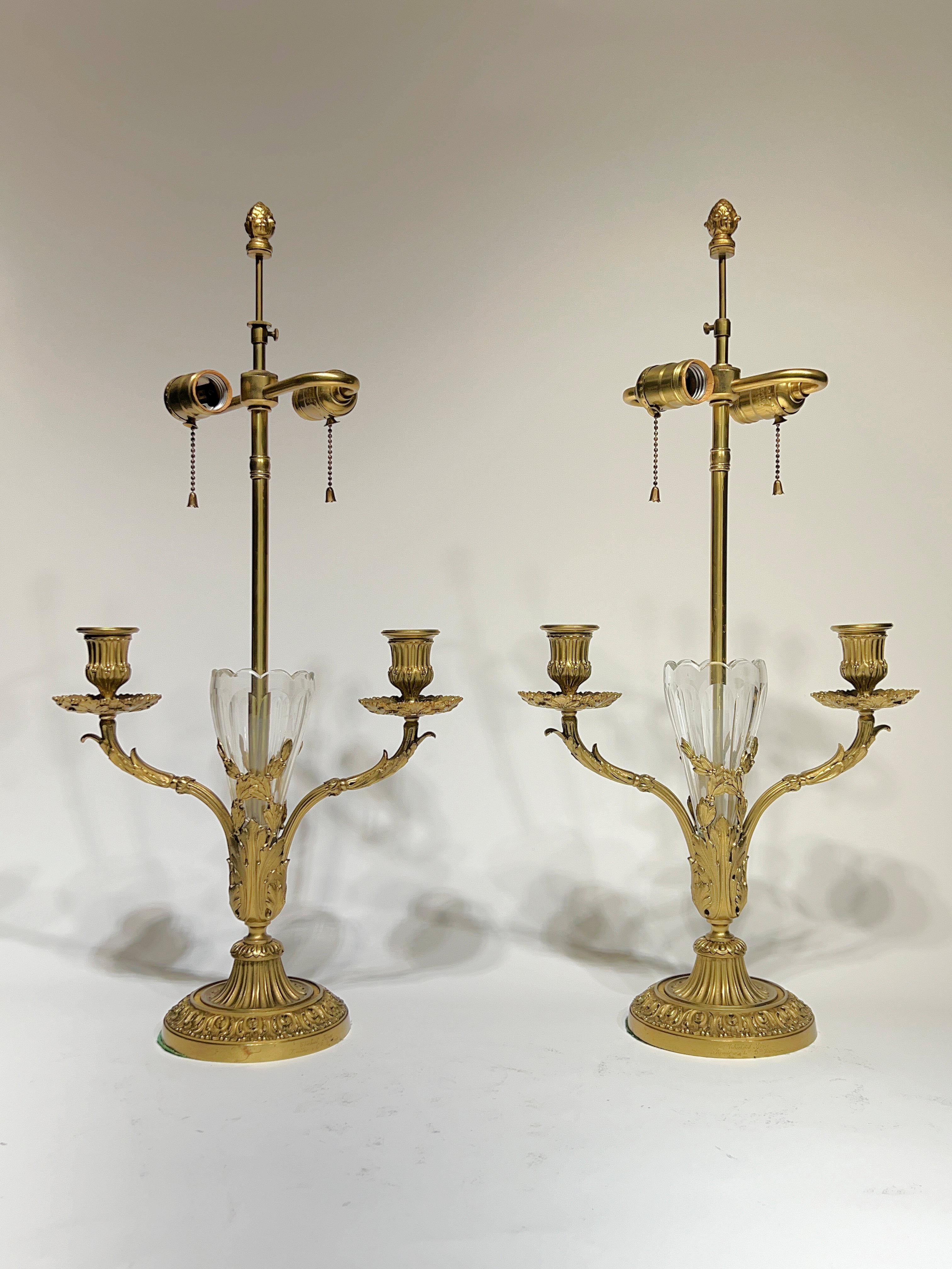 Exceptional pair of antique gilt bronze table lamps in the French Louis XVI style by Thiebaut Freres et Cie of Paris, distinguished by their fluted crystal vases with two original candle arms and  two later standard electric sockets.  Drilled for