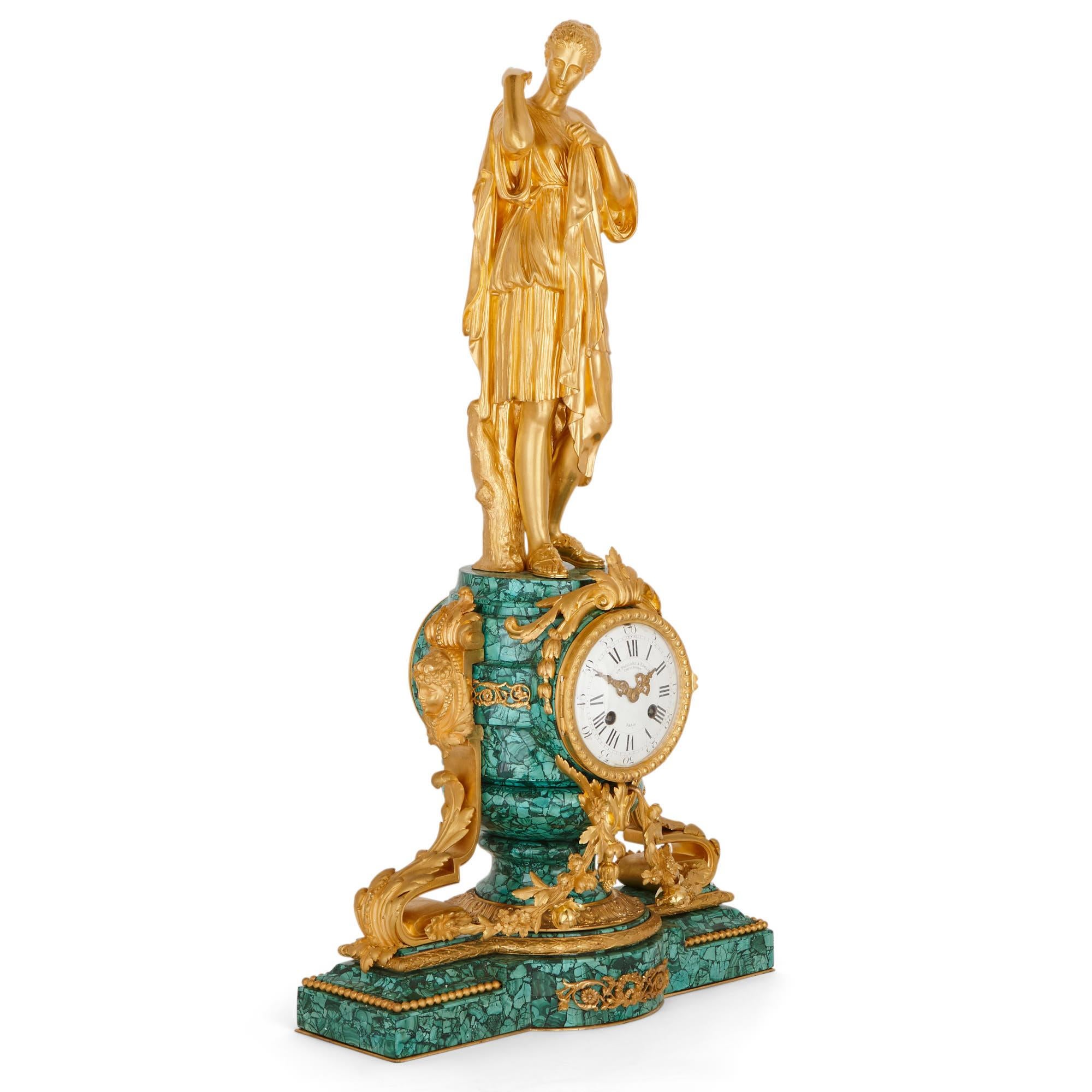 Dieses wunderbare Uhrenset wurde um 1870, Ende des 19. Jahrhunderts, in Frankreich hergestellt. Das Set, das aus einer Kaminuhr und zwei Kandelabern besteht, ist aus vergoldeter Bronze (Ormolu) und dem grünen Edelstein Malachit gefertigt.

Die
