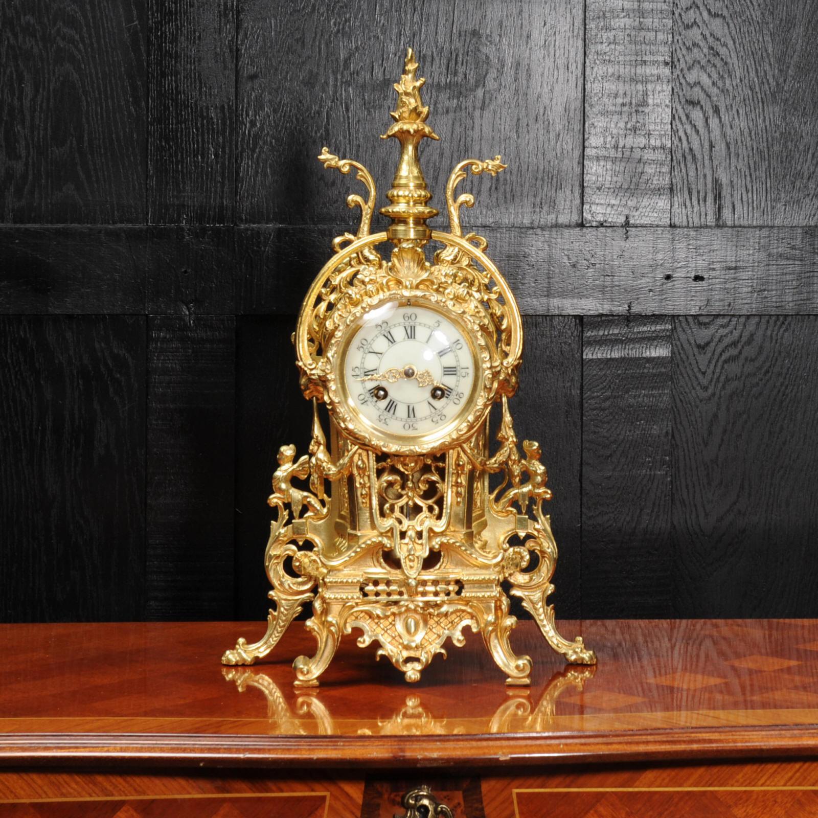 A beautiful original antique French clock in the Baroque style, circa 1890. A tall flaming finial is flanked by the stylised tails of two dolphins. The sides are draped with floral swags and scrolls with mythical creatures. The clock sits on boldly