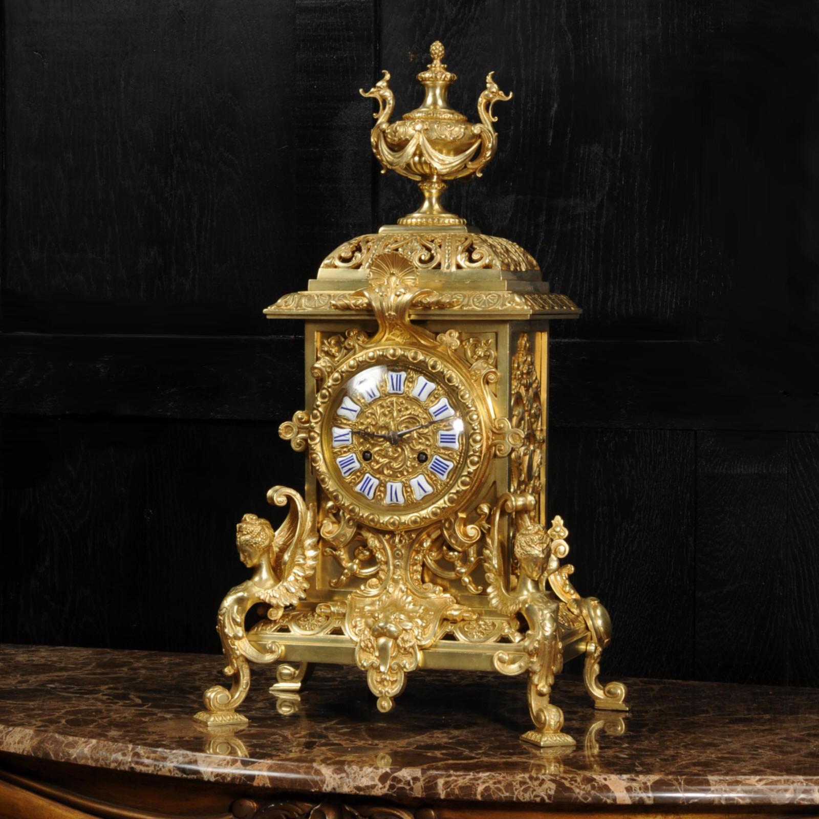 A very large and beautifully detailed and finished original antique French gilt bronze clock. It is Baroque in style, architectural in shape with a fretted bell top with Anthemion Frieze below. Featuring winged goddesses, a lions mask and an