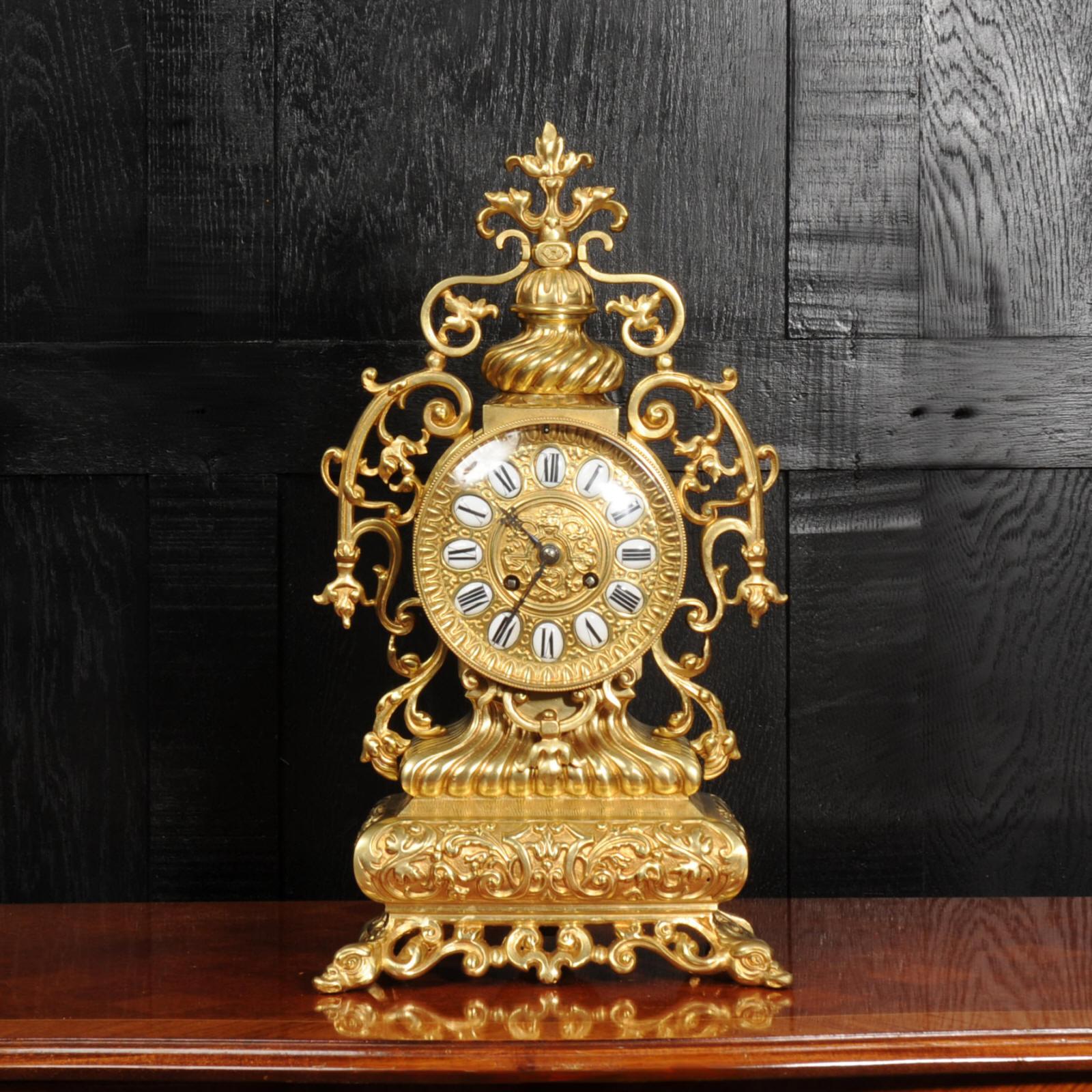 A large and stunning antique French Baroque drum head clock. Beautifully modelled in gilt bronze, the clock sits upon a a cushion shaped base with mythical creatures forming the feet. A swept gadrooned support holds the clock in a drum with