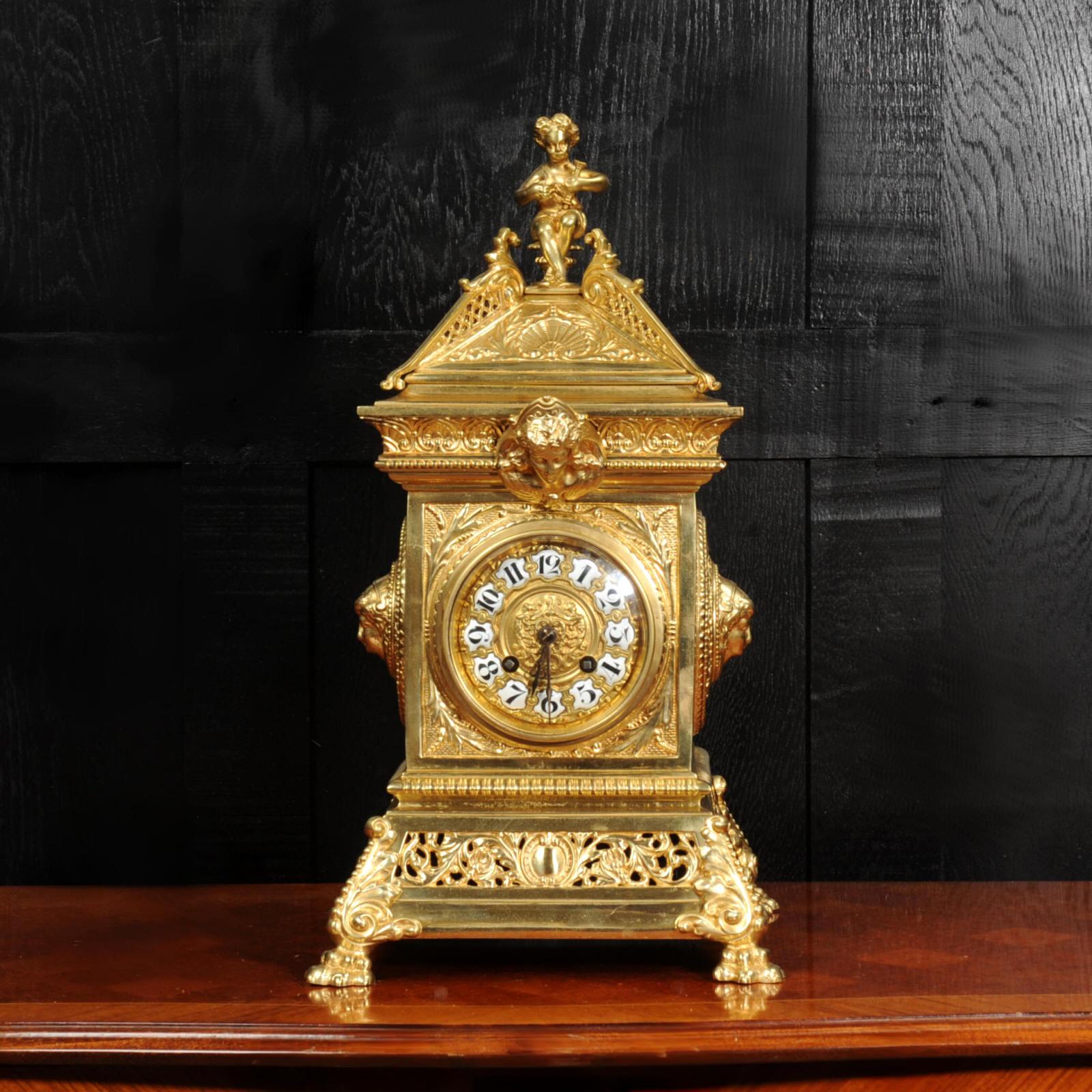 A Large and beautiful antique Baroque table clock. It is very well modelled in gilt bronze. Square, architecturally designed case with goddess masks, acanthus decoration and a cherub to the top. The base is formed of fretted acanthus and it stands