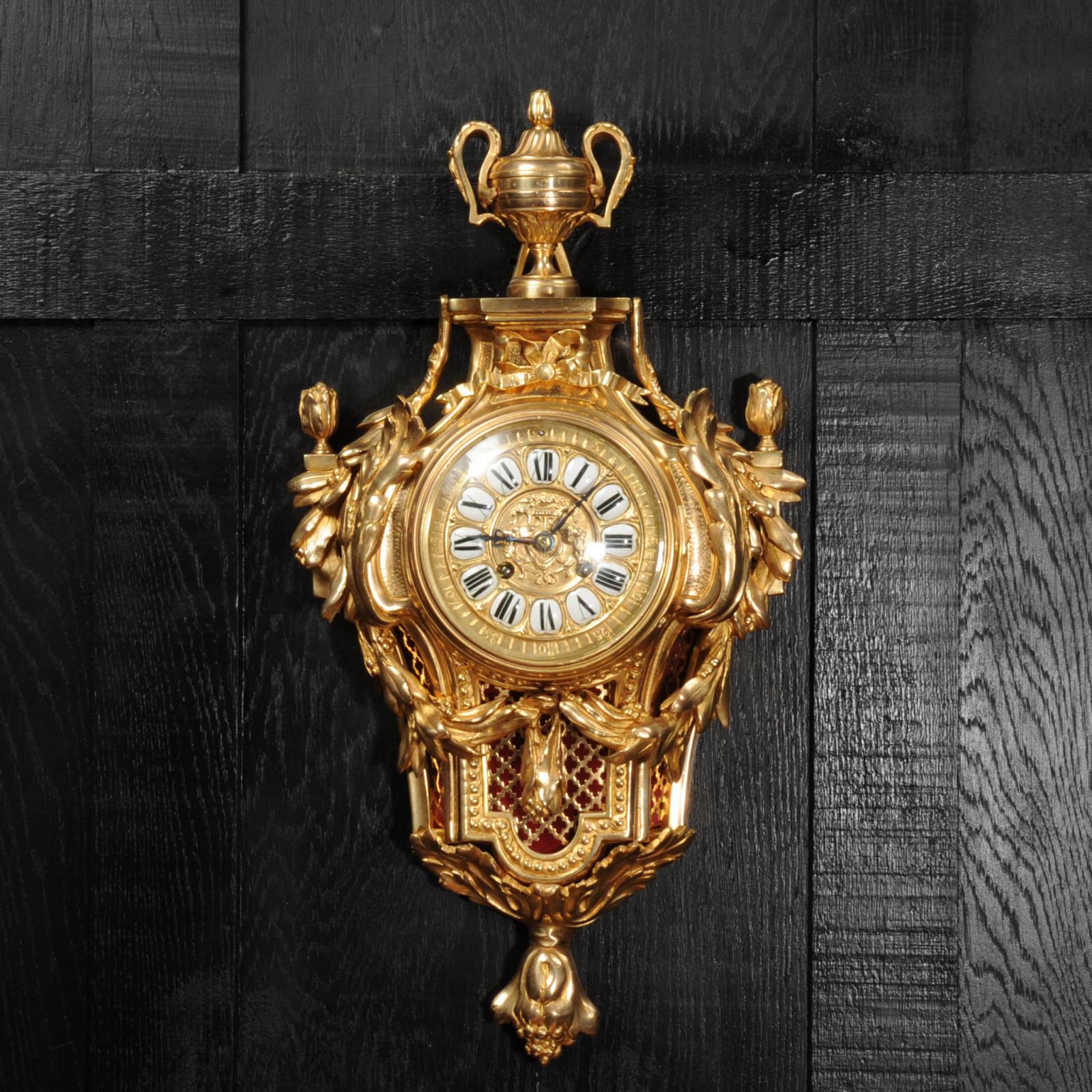 A very elegant cartel clock, Louis XVI in design with a handled urn and acanthus decoration. A large bow sits above the dial, and sound panels to the sides and front allow the delicate sound of the bell strike to be heard. It is finely made in
