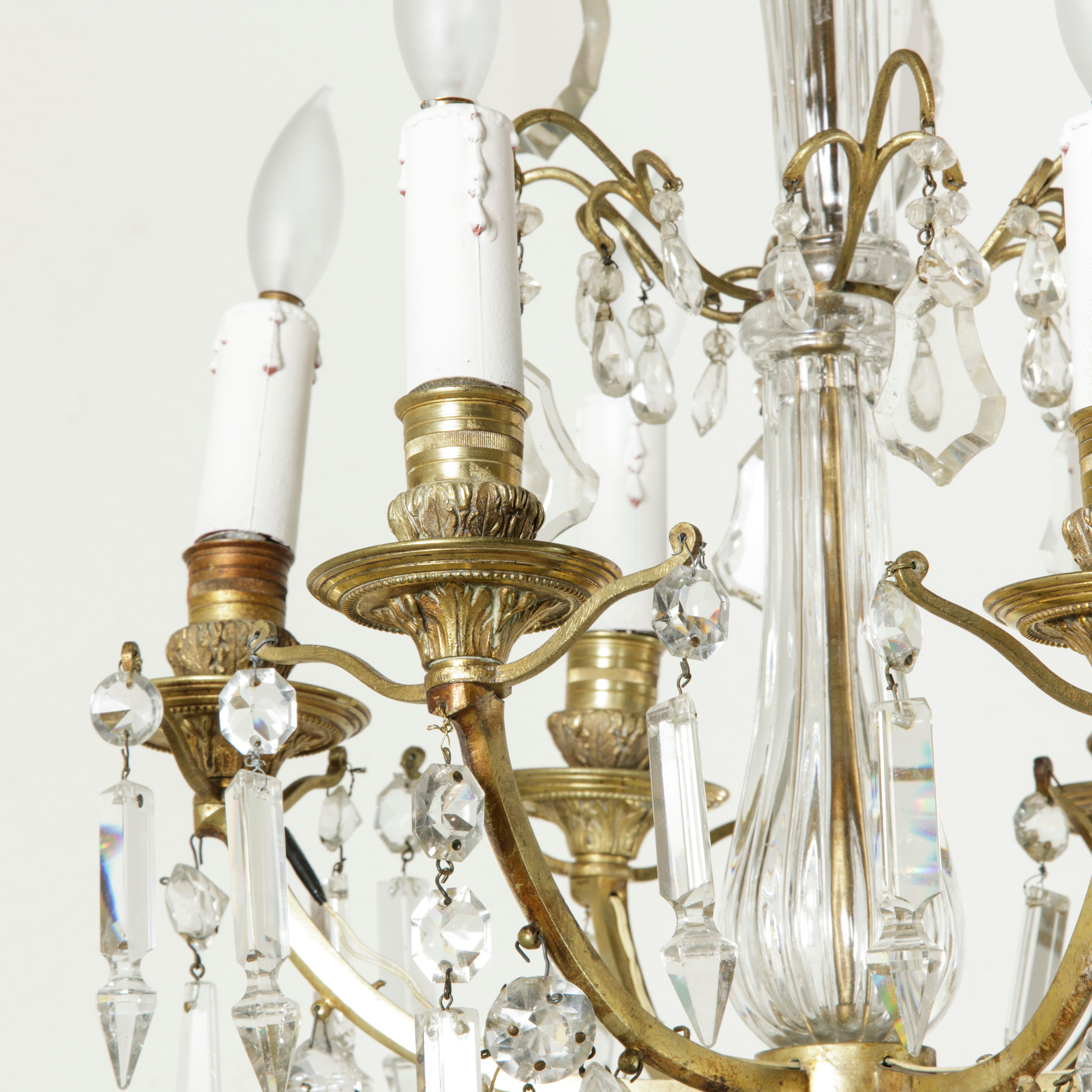 This elegant crystal chandelier is beautifully detailed. Its six arms are heavily draped with pendalogues and spears while its central crystal column leads to two more tiers with large pendalogues. The fantastic bronze canopy consists of six