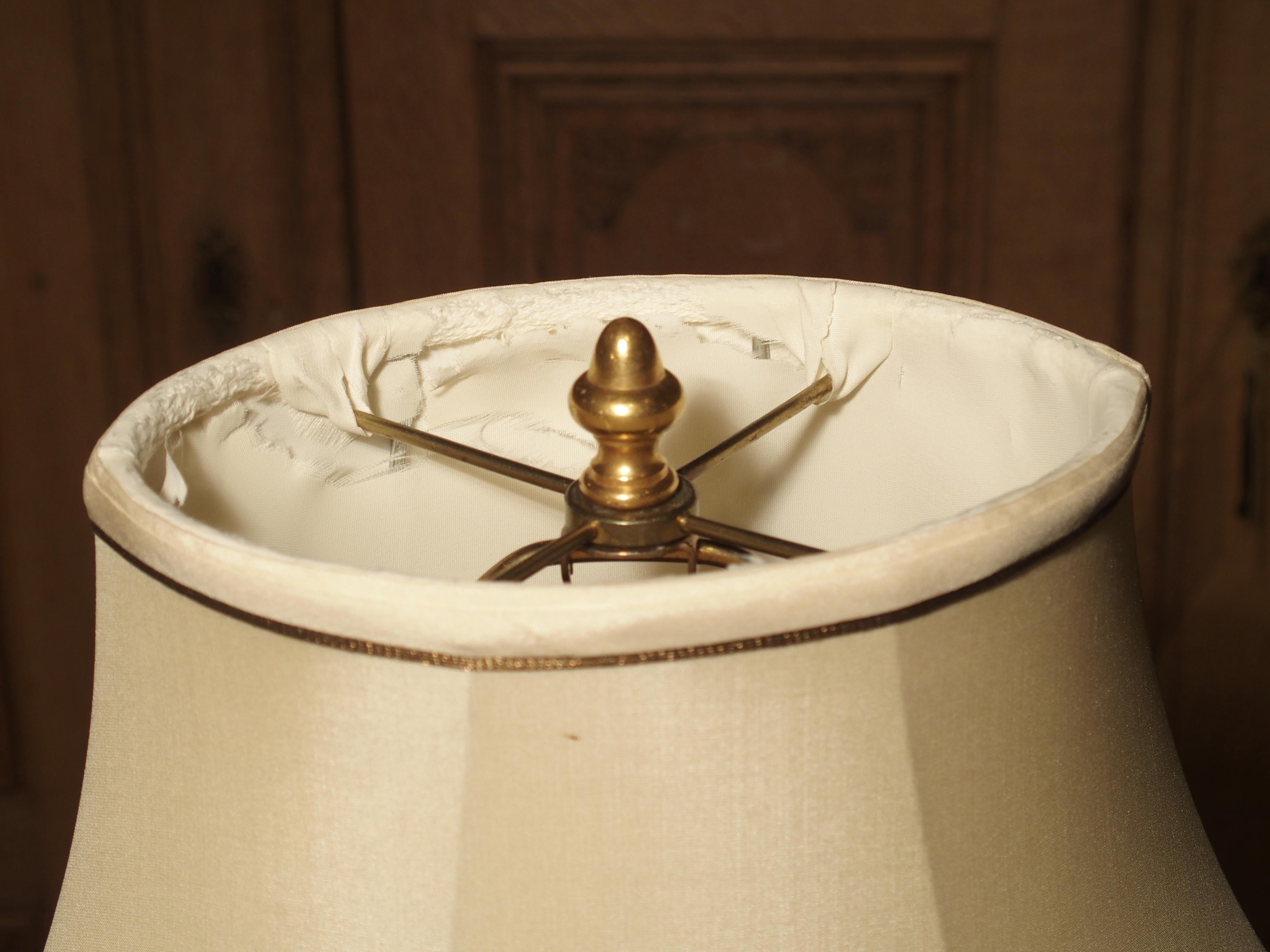This elegant French table lamp is made from a late 19th century bronze. The cherub wears a drape over his lap and has an open book in one hand. He sits on a rocky ledge with sparse foliation (separately cast piece). All this is mounted to an oval