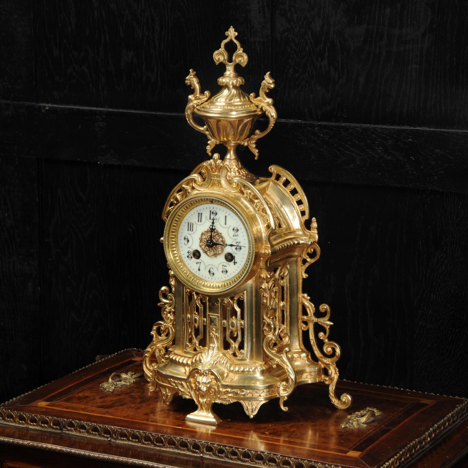 A stunning original antique French gilt bronze clock, circa 1900. It is modelled in the Baroque style with acanthus decoration and a large, elaborate urn. The front and sides are fretted to allow the pendulum to be seen gently swinging within. It