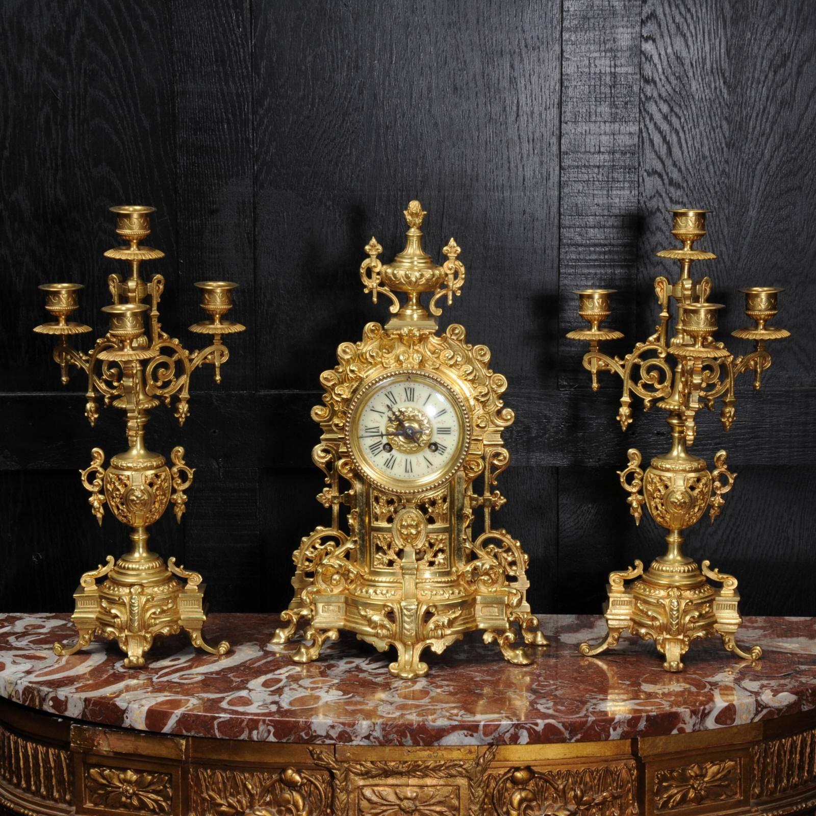 A lovely original antique French gilt bronze clock set, circa 1880. Classical in design with elaborate acanthus decoration, fretted to the front to allow the pendulum to be seen gently swinging within. Candelabra are conforming in style with three