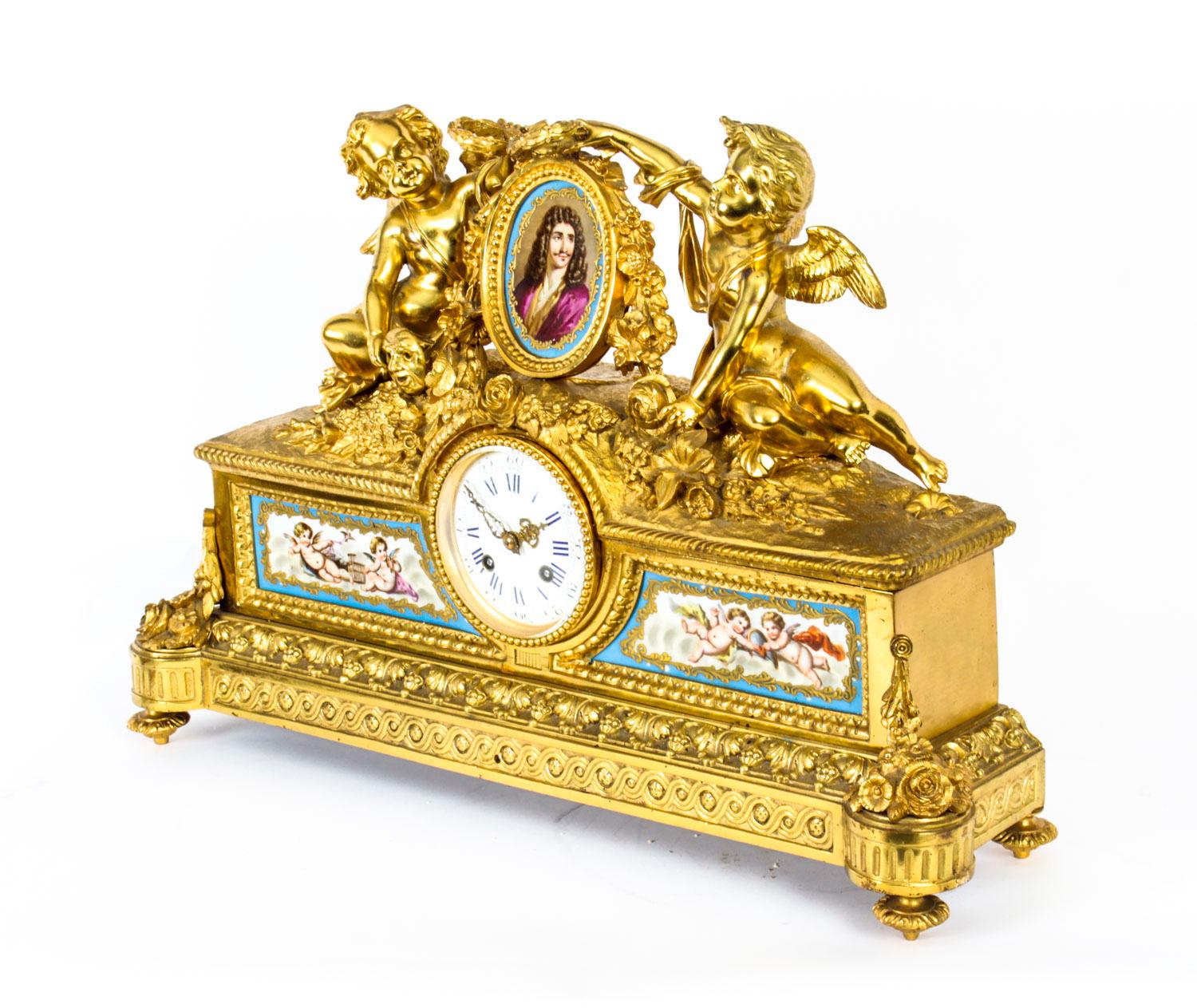 This is a superb antique French gilt bronze mantel clock with Bleu Celeste porcelain panels in the Sevres manner, circa 1860 in date. 

The case crowned with two cherubs holding laurels one holding a mask emblematic of theatre, flanking an oval