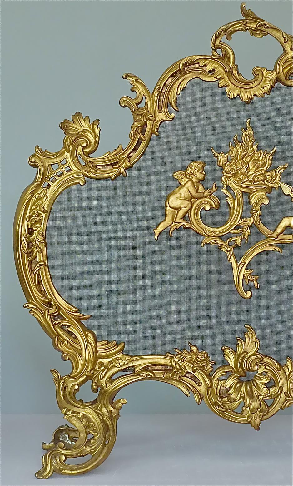 Amazing 19th Century French antique gilt bronze free standing ormolu fire place screen in Louis XV Rococo Style with floral handle, flanking scrolled acanthus motif, highlighted with a center medallion showing winged cherubs tending to a flame, and