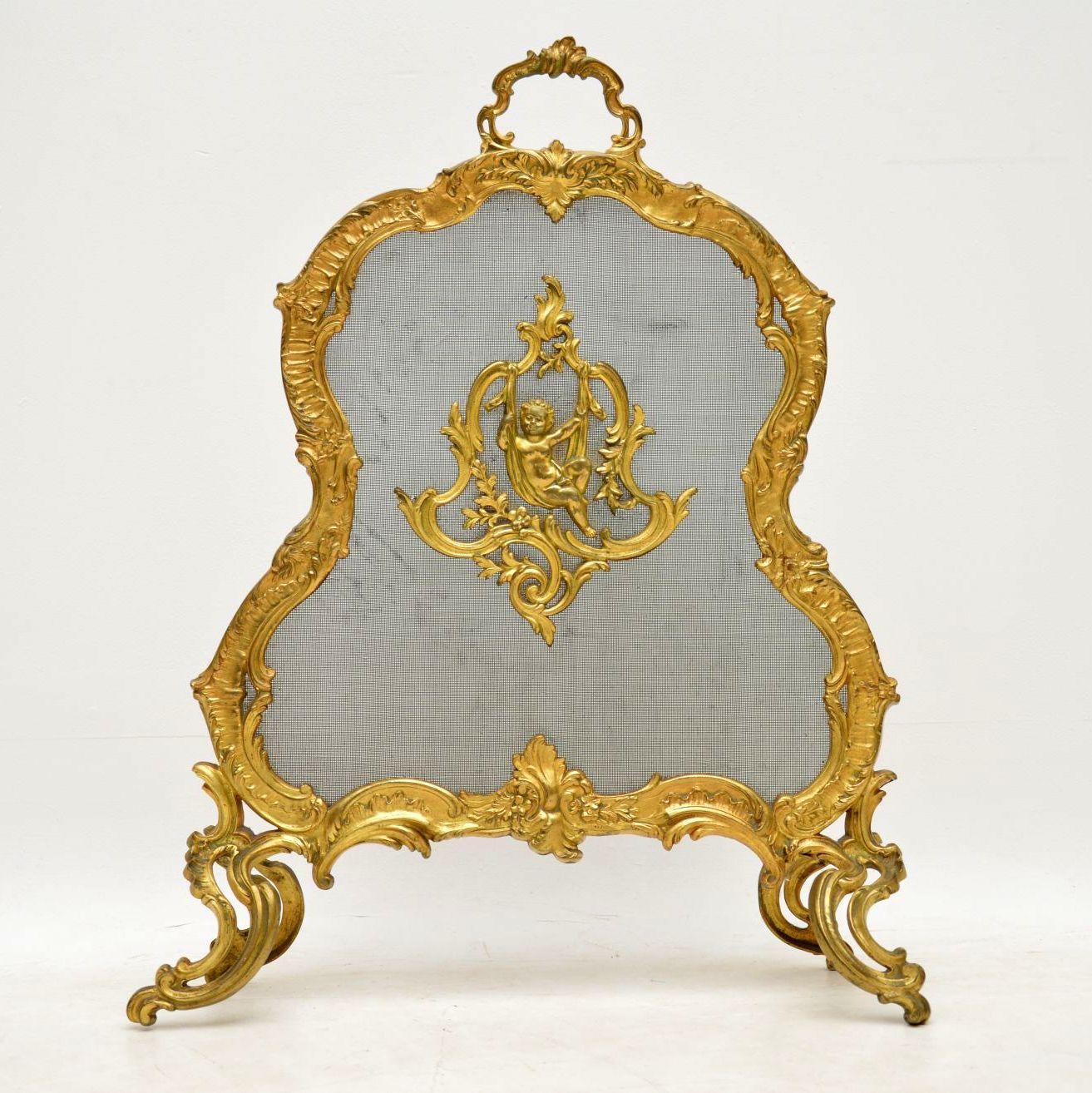 Antique French gilt bronze highly ornate and decorative fire screen in the Rococo style, with a playful cherub fixed in the middle on a wire mesh background. This piece has a lot of detailed castings and embellishments. It’s in good condition and