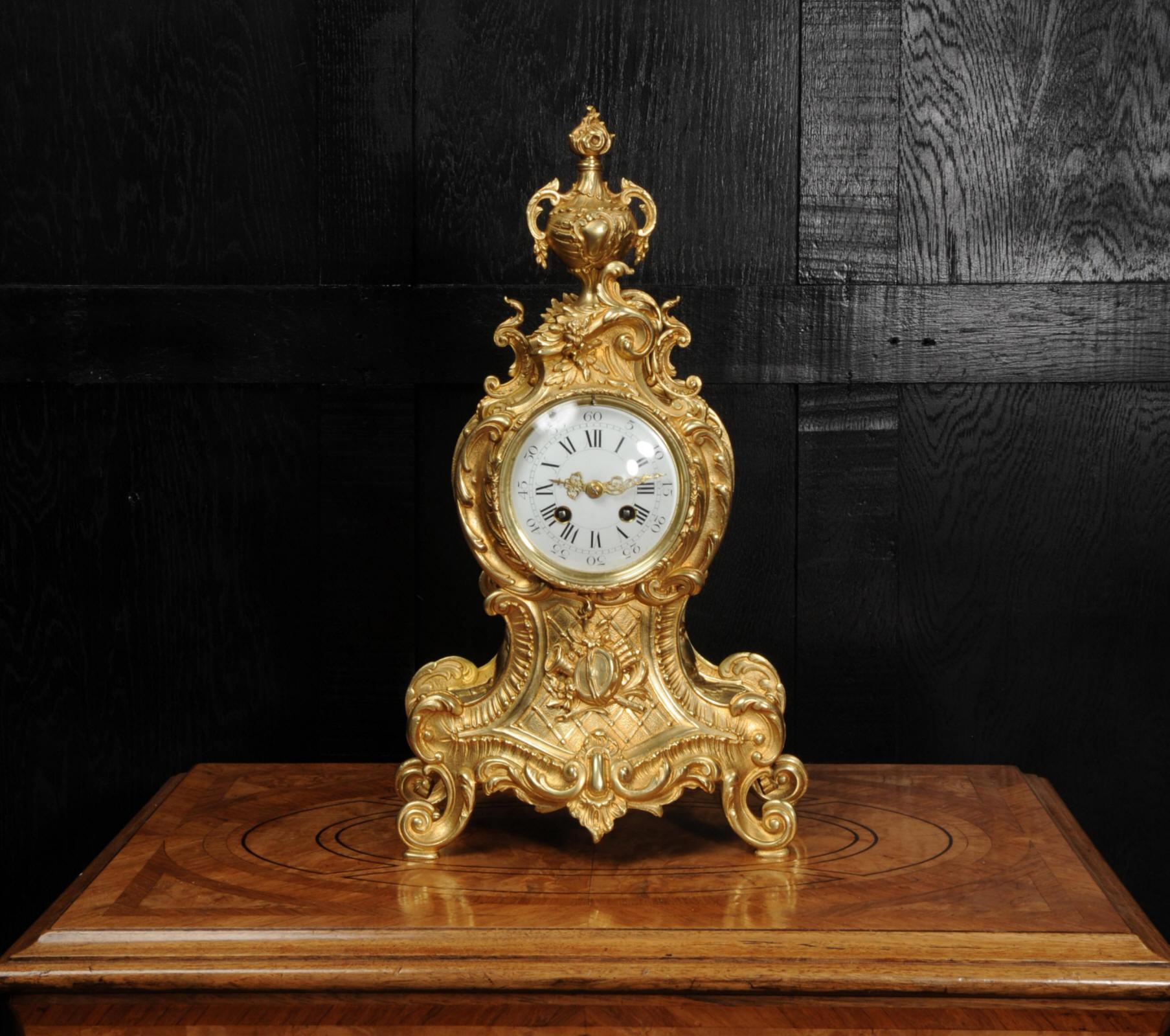 A superb original antique French Rococo clock, circa 1900. It is beautifully modelled in gilded bronze, of waisted shape, profusely decorated with 'C' scrolls, acanthus leaves, shells and trailing foliage. To the top is an elaborate handled urn and