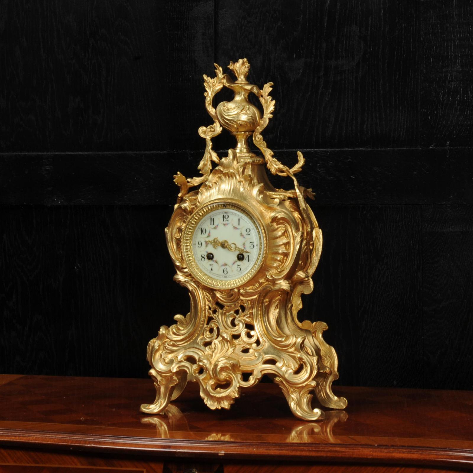 A stunning original antique French Rococo clock, dating from around 1880. It is beautifully modelled in gilded bronze, of waisted shape, profusely decorated with 'C' scrolls, acanthus leaves and trailing foliage. To the top is an elaborate urn with