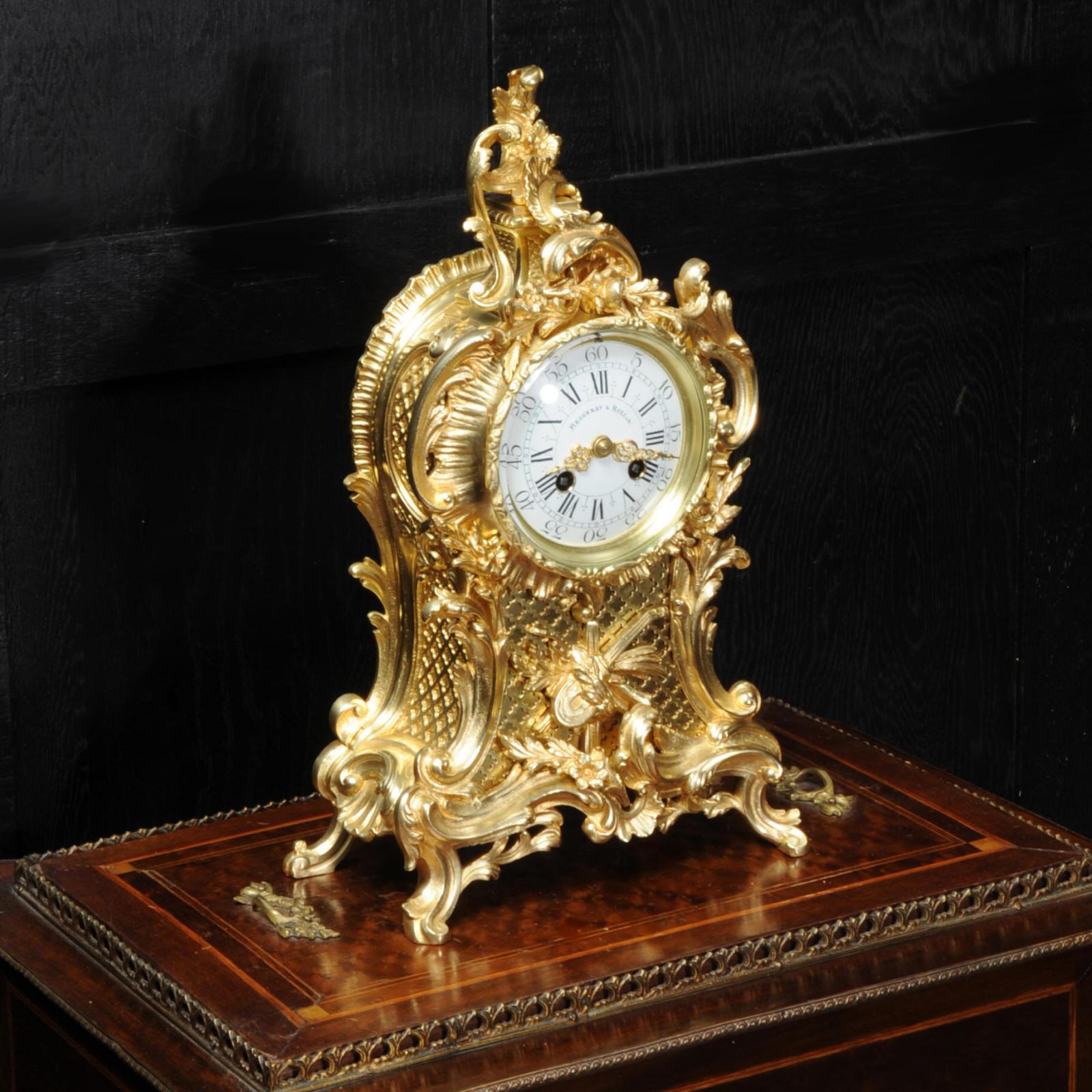 A lovely original antique French Rococo clock by Vincenti et Cie, circa 1880. Flamboyantly modelled in gilded bronze, waisted case with with swirling acanthus, 'c' scrolls and floral swags. To the front is a panel of fret work with a motif of