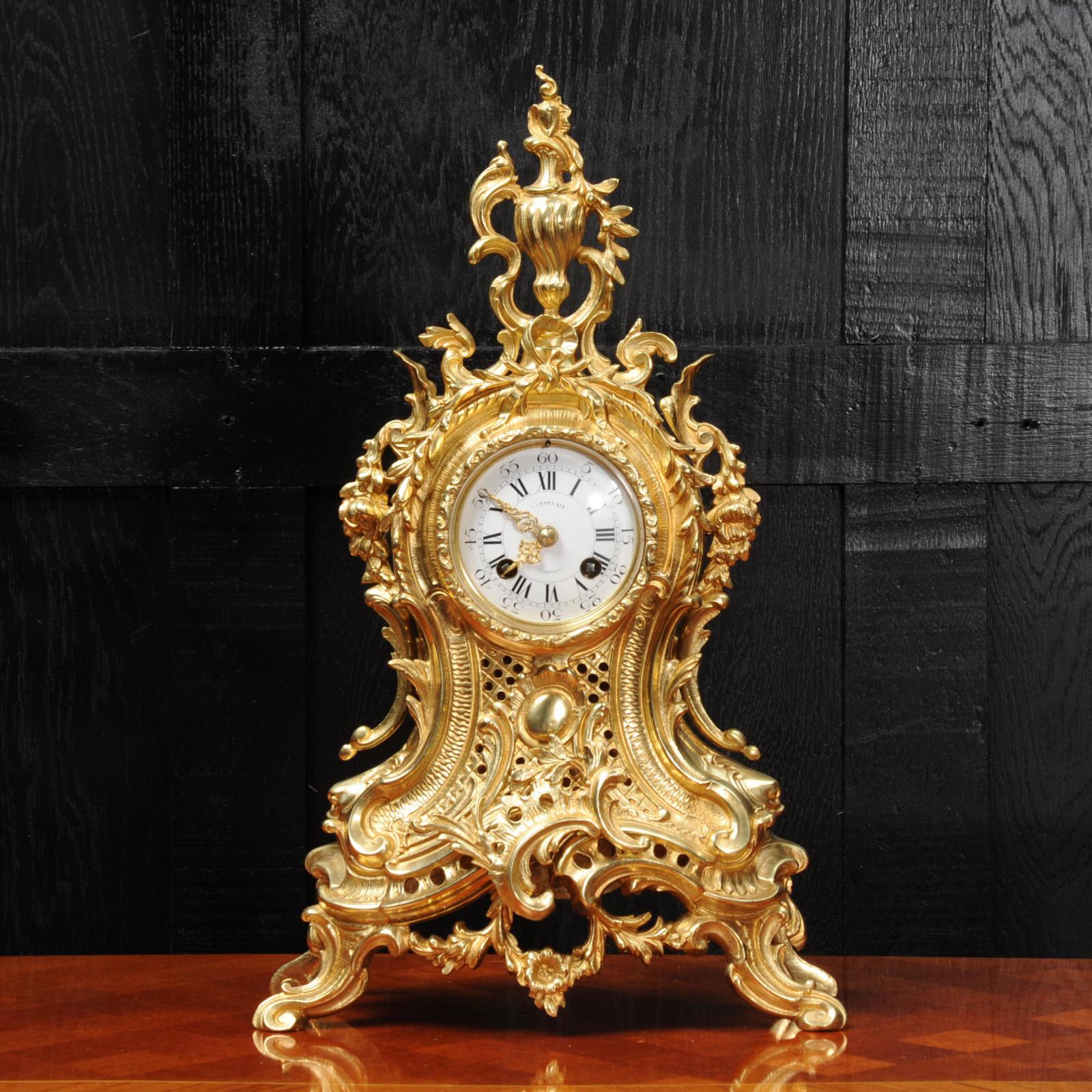 A lovely original antique French clock, boldly modelled in the Rococo style in gilded bronze, circa 1890, it is finely detailed with an elaborate asymmetric urn, profuse floral swags and 'C' scrolls. The front of the case is fretted, allowing a
