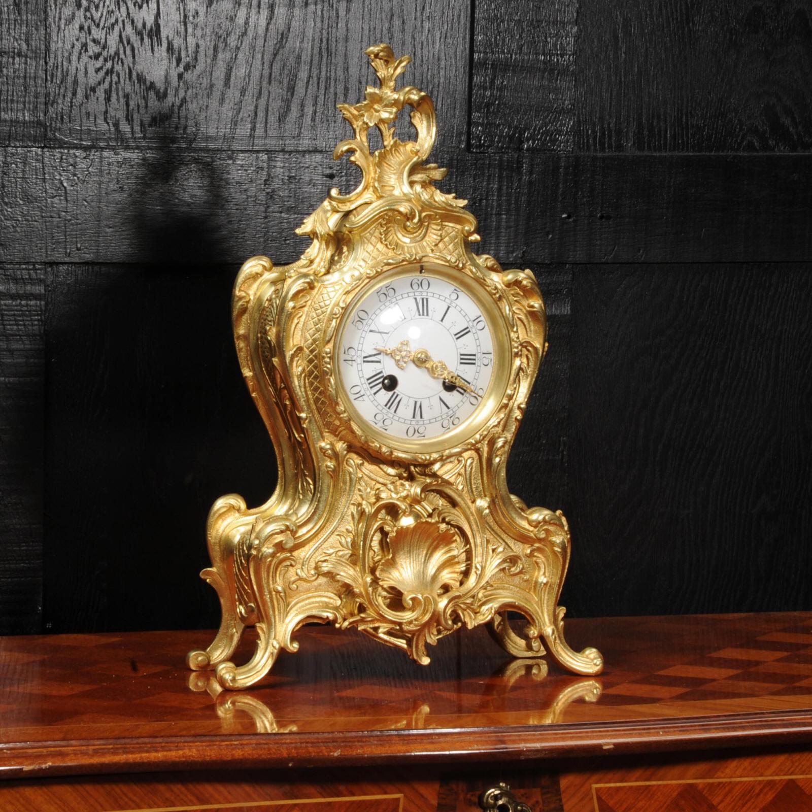 A lovely antique French clock by A. D. Mougin, circa 1900. It is boldly modelled in the Rococo style in gilded bronze. Waisted keyhole shape profusely decorated with 'C' scrolls, and acanthus to the shoulders. A large shell motif is mounted to the