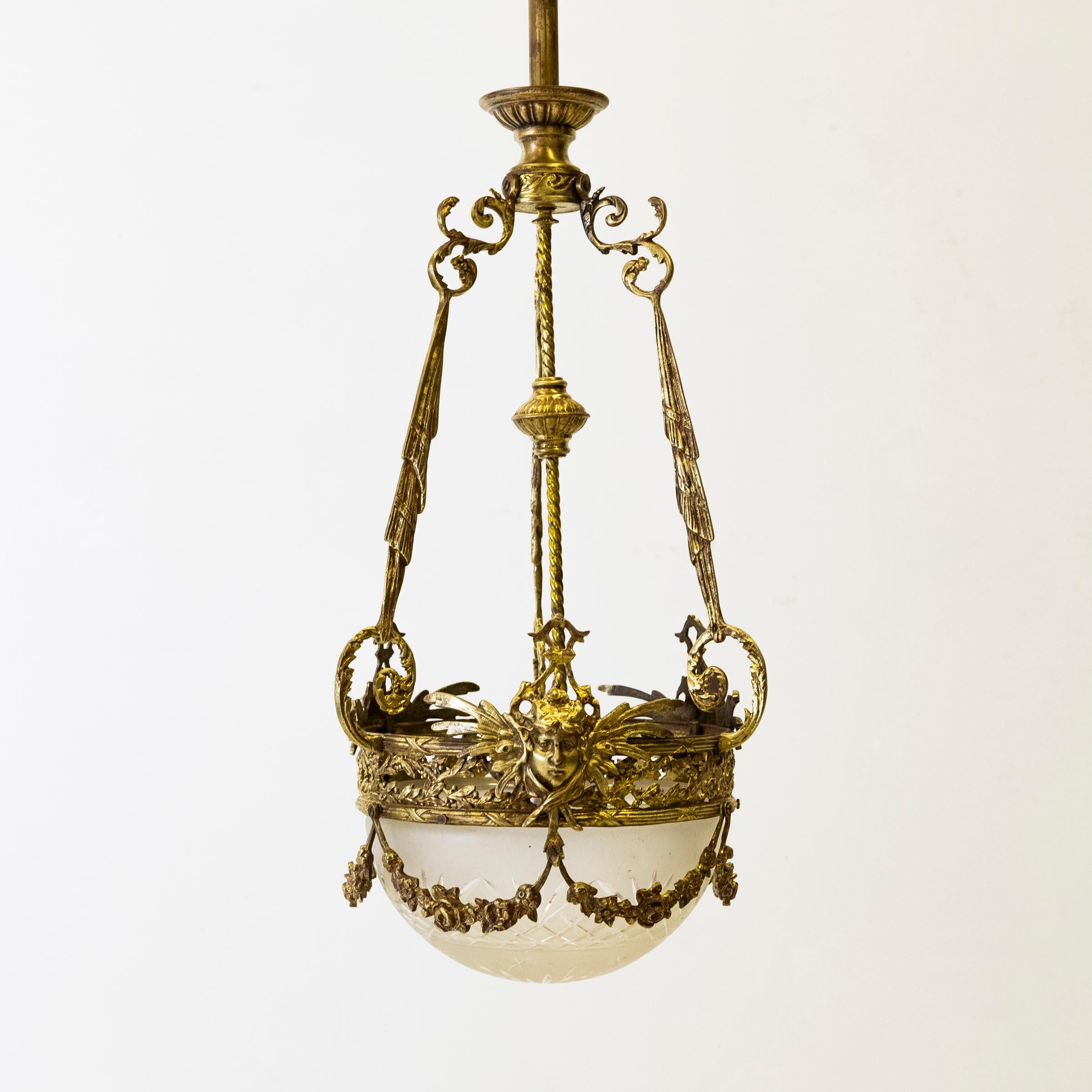 Ce charmant plafonnier français en bronze doré est doté d'un bol en verre dépoli et profondément taillé, solidement maintenu par un anneau circulaire orné de détails complexes.

Cette opulente pièce ancienne présente des volutes élaborées et est