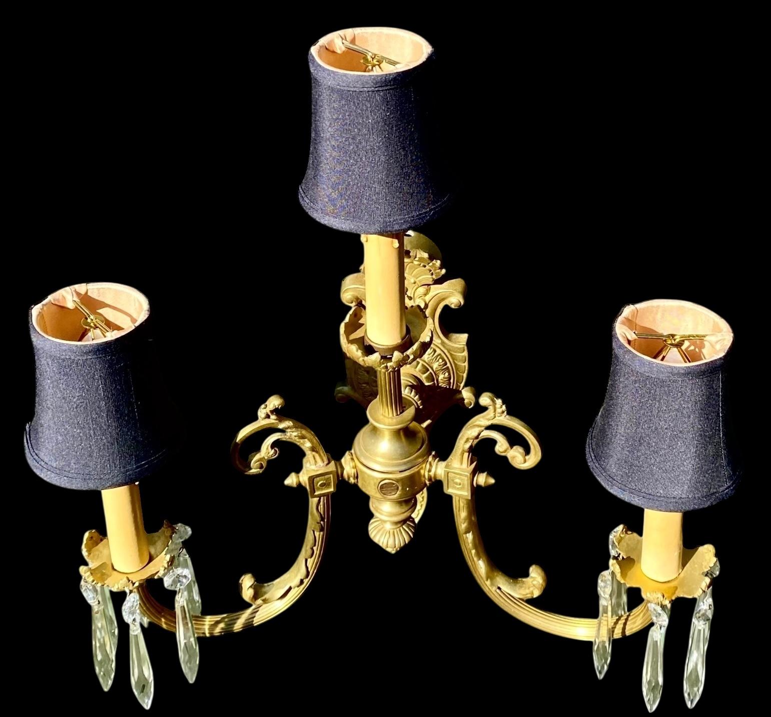 Antiguo candelabro de bronce dorado estilo Luis XIV de la Belle Époque francesa, con tres luces de bronce dorado finamente cincelado y detallado. 
Los dos brazos elaboradamente curvados a los lados con bobesch florales adornados con prismas de